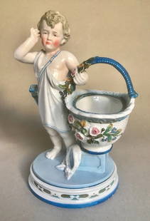 Antique KPM German Porcelain Figure of Angel/Cupid With Flower Basket: Antique circa 1880 K.P.M. German porcelain figure of an angel/cupid with a flower basket. This cupid is pictured as a young boy bringing the basket that is supposed to be filled with flowers. The