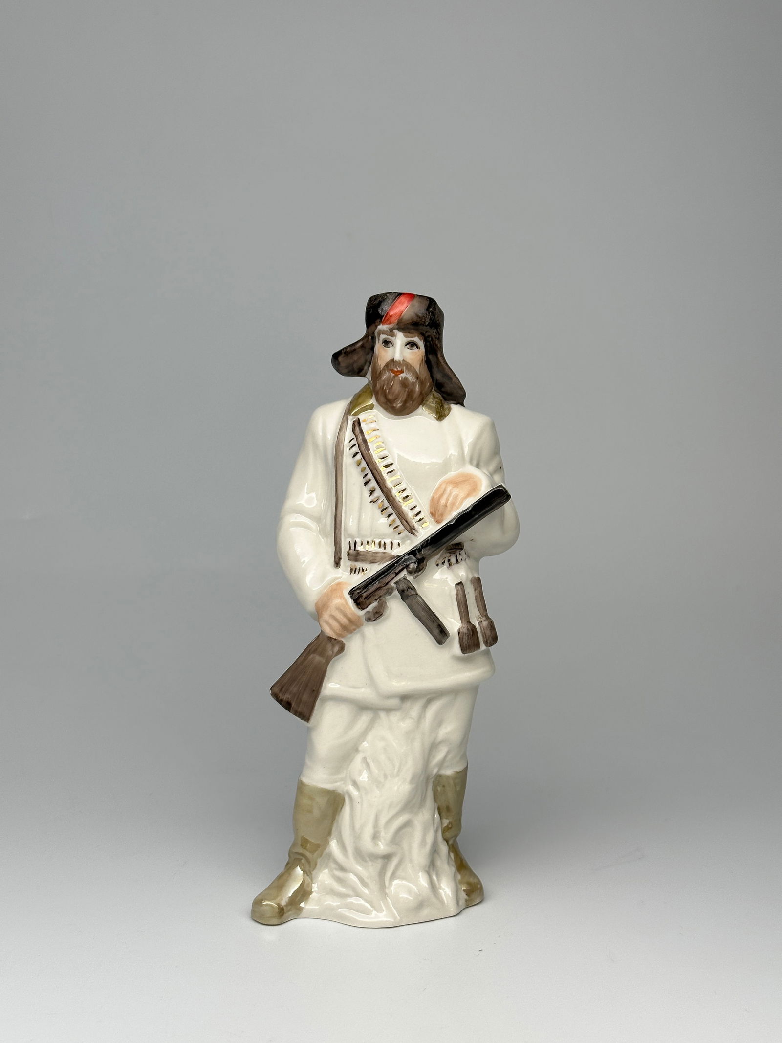Soviet WWII Porcelain Figurine "The Partisan" Grist O.V.: Depicted here is a Soviet WWII era partisan fighter. Shown as an older man with a beard dressed in winter clothing and armed with a submachine gun, several grenades and a belt of ammunition across his