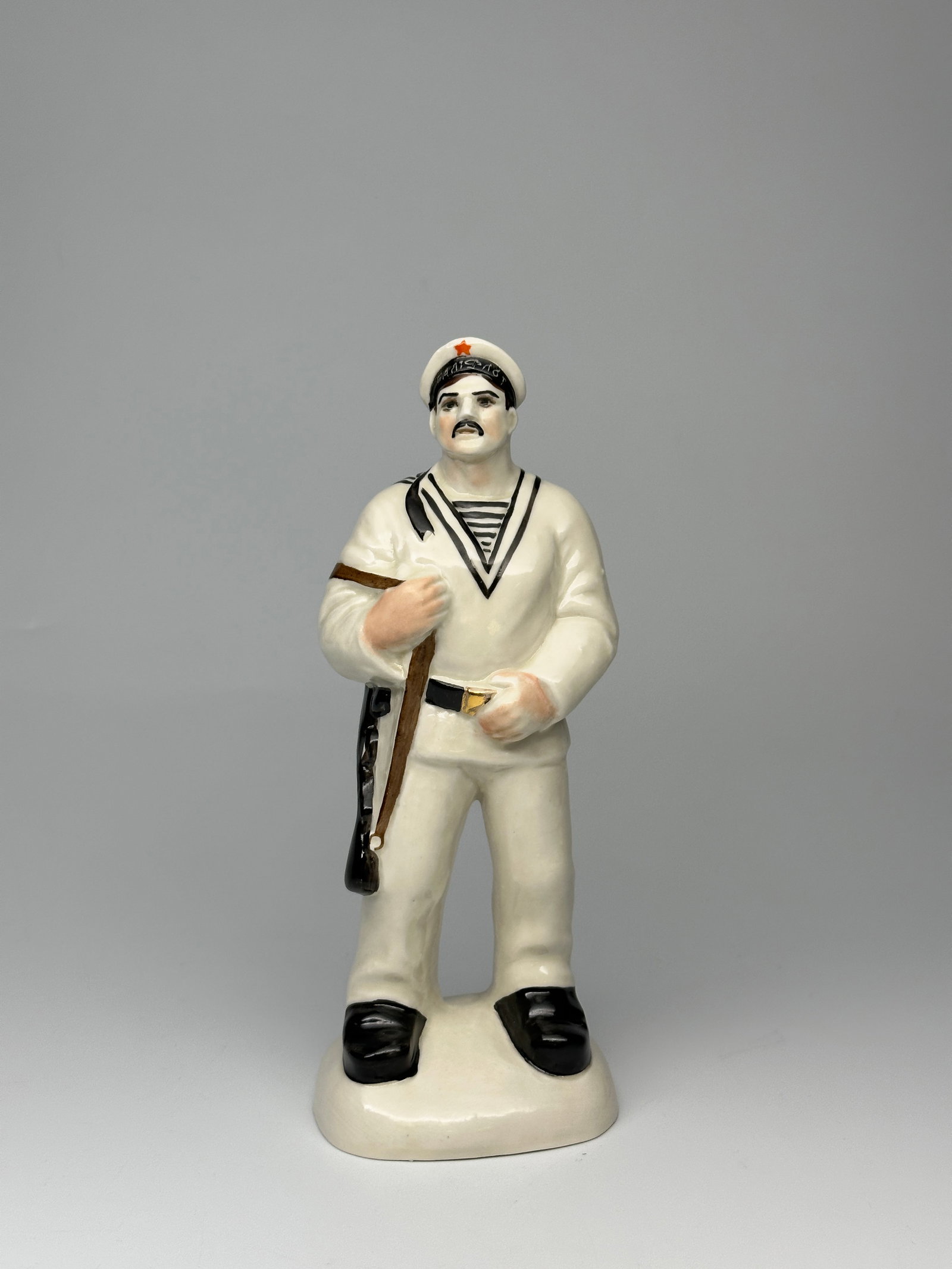 Soviet WWII Porcelain Figurine "The Sailor": Depicted here is a Soviet WWII era sailor. Shown as an younger man with a mustache dressed in his sailor uniform and armed with a rifle. On the bottom of the figurine is the authors inscription "NAZAR
