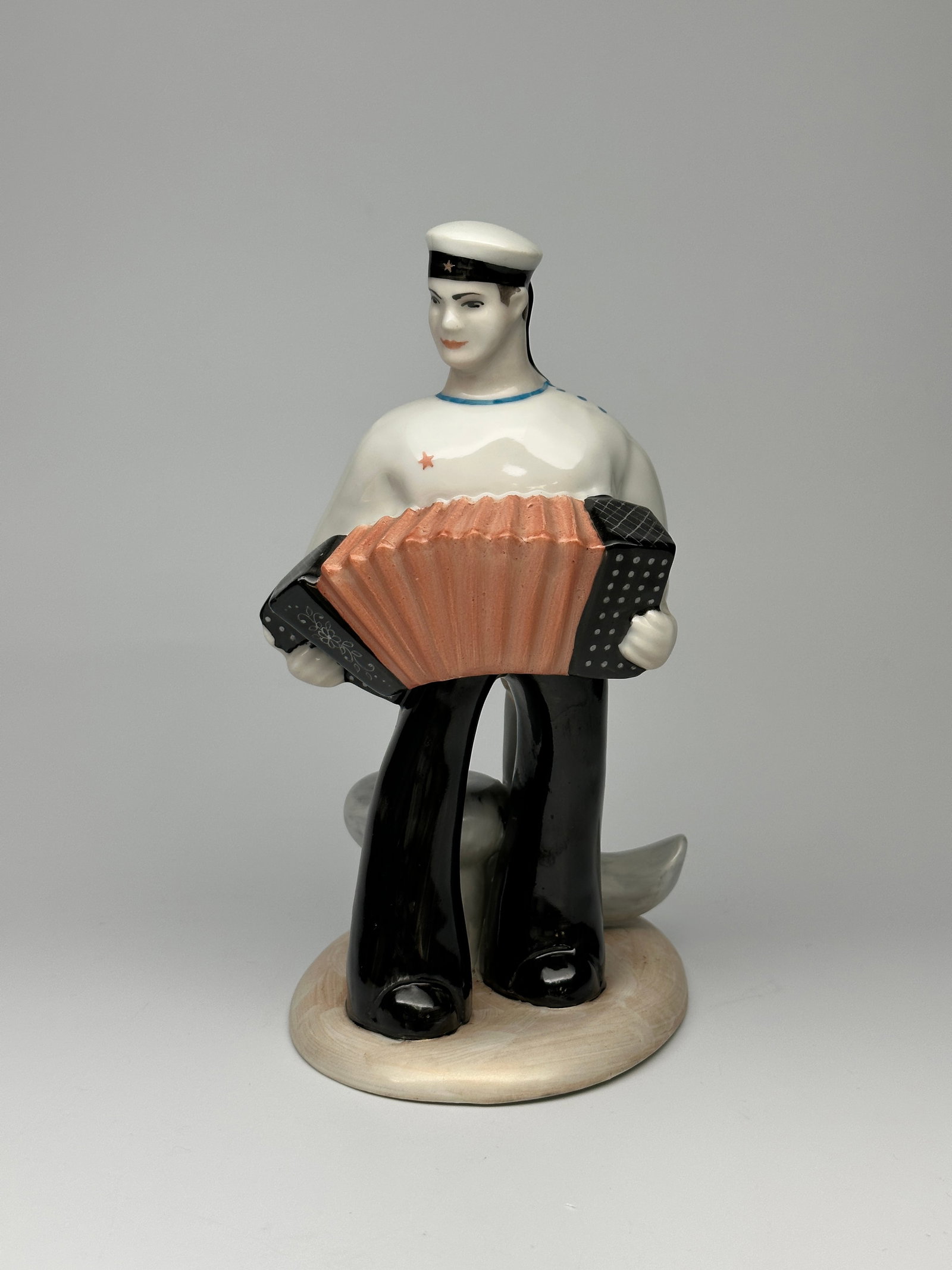 Rare Vintage Soviet Porcelain WWII Figurine "Sailor playing the acordian" Baranovka Porcelain: A Soviet Porcelain WWII Figurine of a Sailor playing the acordian in front of a giant ship anchor. Makers mark on underside. Signed "Prisyazhnyuk” Presented here is a marvelous selection of porc