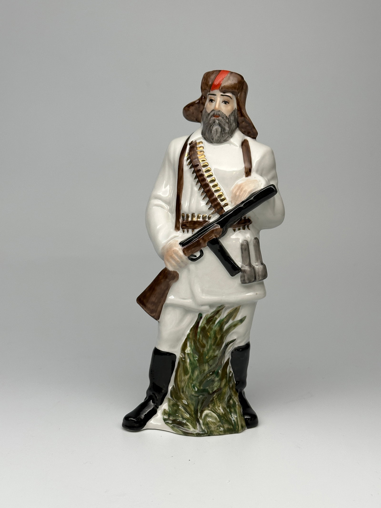 Soviet WWII Porcelain Figurine "The Partisan" Grist O.V.: THIS IS A DIFFERENT LOT FROM LOT 112 Depicted here is a Soviet WWII era partisan fighter. Shown as an older man with a beard dressed in winter clothing and armed with a submachine gun, several grenade