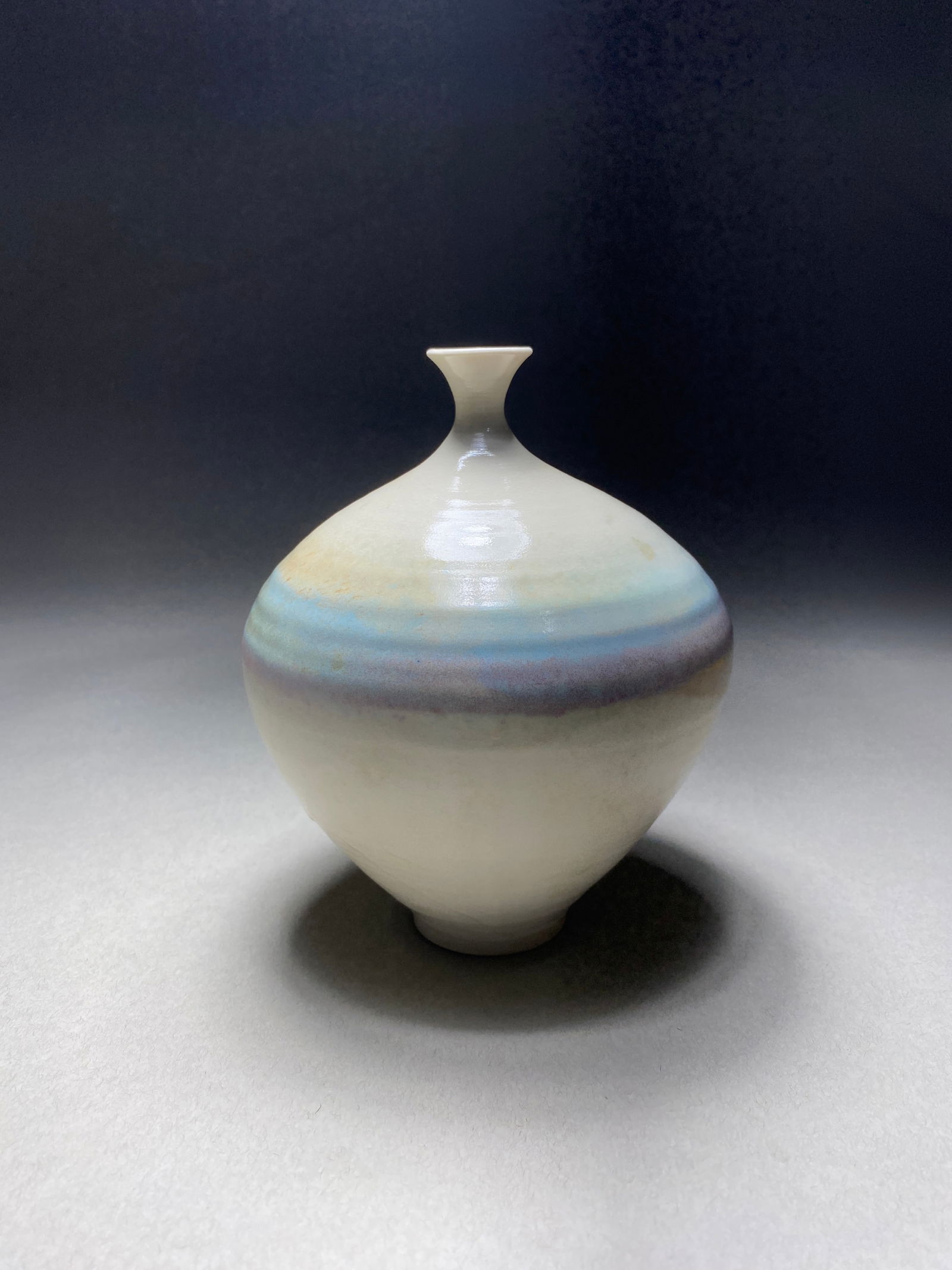 Contemporary Ceramic Studio Vase with Aurora Borealis Glaze: Contemporary Ceramic Studio Vase with Aurora Borealis Glaze A refined porcelain vessel featuring an elegant spherical form with a gracefully tapered neck. The surface showcases a band of ethereal colo