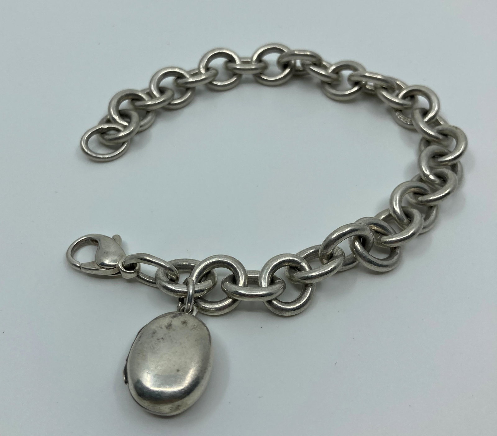 Tiffany & Co, Sterling Silver Locket Bracelet: Artist : Tiffany & Co Titre : Sterling Silver Loquet Bracelet Description (FR) : Bracelet en argent sterling, contenant un medaillon a photographie, signee au milieu du bracelet T&Co .925 et sur le me