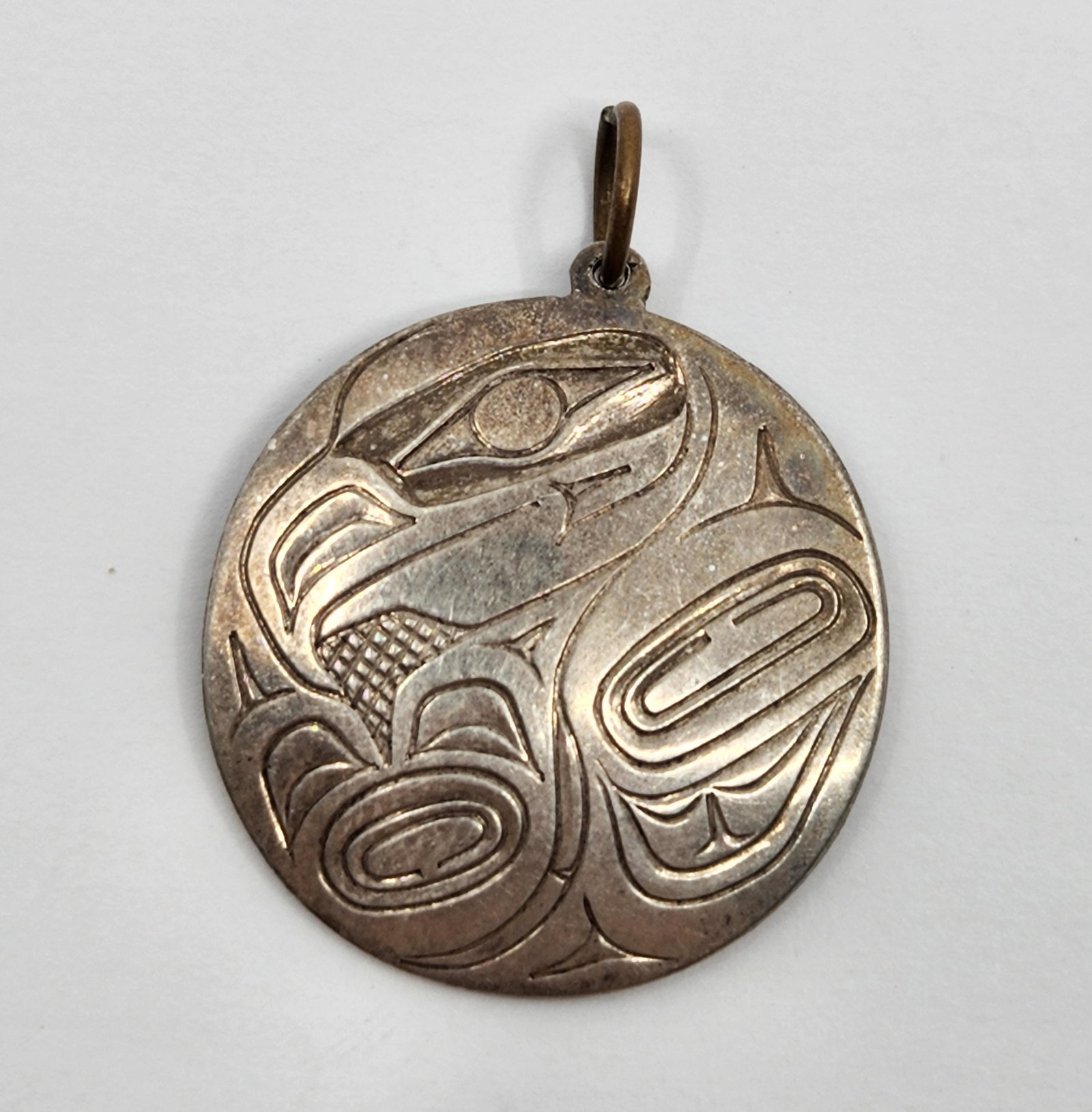 Jim McGuire (1953- ), Haida, North West Coast, Raven Sterling Silver Pendant: Artist : Jim McGuire (1953- ), Haida, North West Coast Titre : Gilbert Pat (1945- ), Haida, North West Coast, Eagle Sterling Silver Brooch Description (FR) : Pendentif en argent sterling, representant