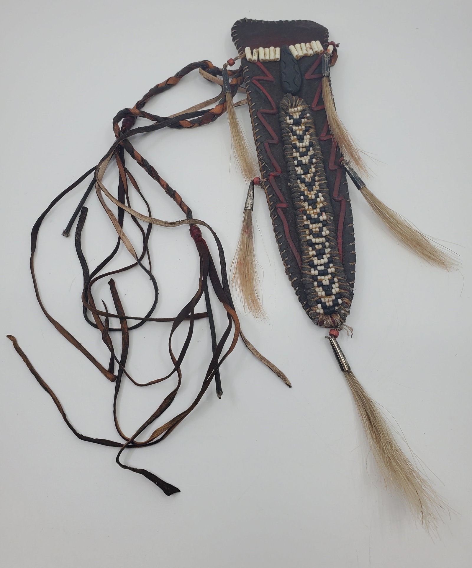 Antique Indigenous Knife Sheath: Entirely hand made of leather, and decorated with white and black beads, possibly bone. carced wood. woven strips os different coloured leather,a few red beads at junctures, and metal capped horse's h