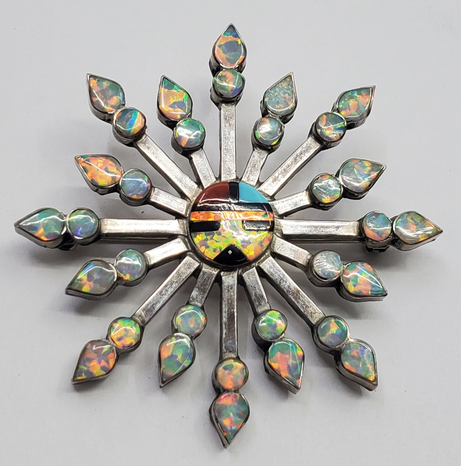 Vera Halusewa, Zuni Sterling Silver Sun Face Brooch Pendant: Sterling Silver Brooch Pendant, set with Opales, Red Coral, Turquoies and Onyx, Signed on the back V. Halusewa Sterling Size : 1 3/4" x 1 3/4" Weight: 8,3 g