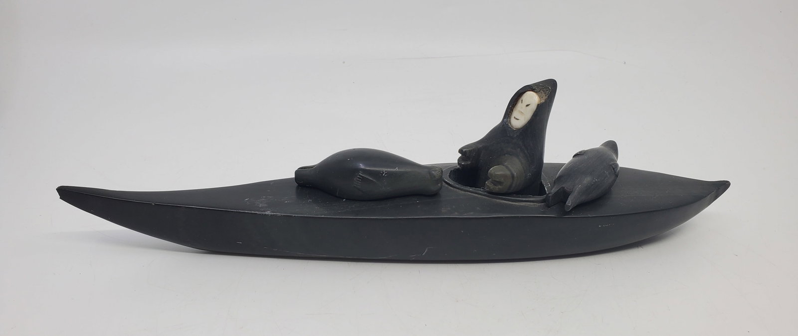 unidentified ARTIST, INUIT,Man on Boat with Seal's: Serpentine Stone sculpture with bone inset, unmarked 3" x 12" x 2"