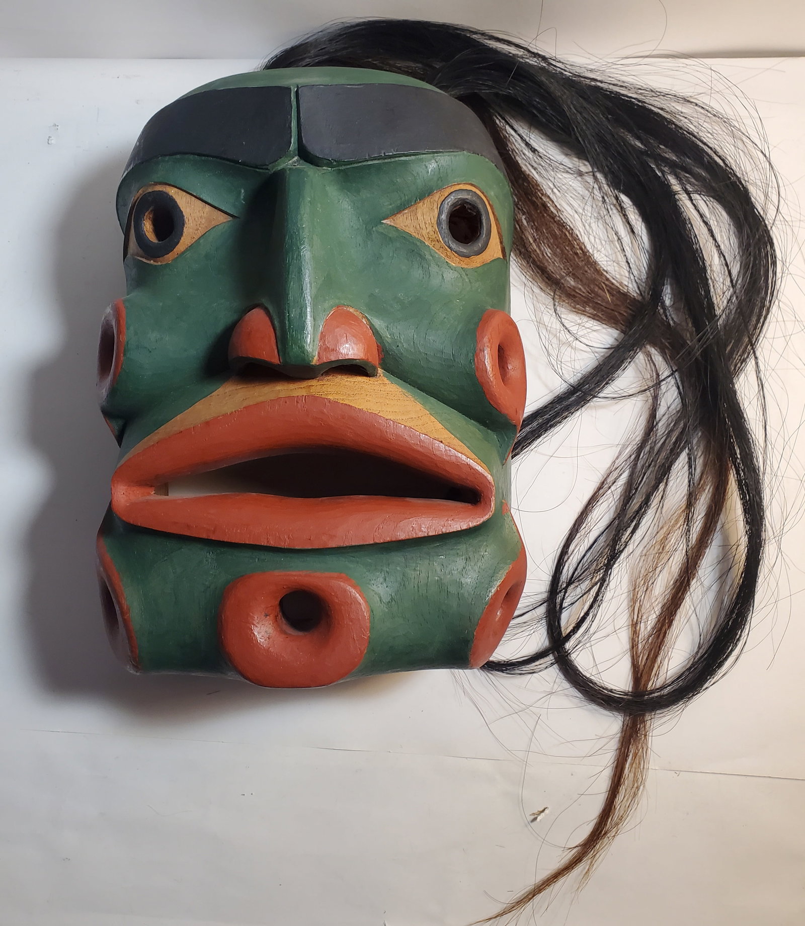 Indigenous Northwest Coast Ceremonial Carved Wood Mask with Horsehair: Probably mid 20th century.Appears to represent Bokwas, or "Wild Man of the Woods". There is a probable signature mark inside. 5 1/2 x 9 3/4 x 13".