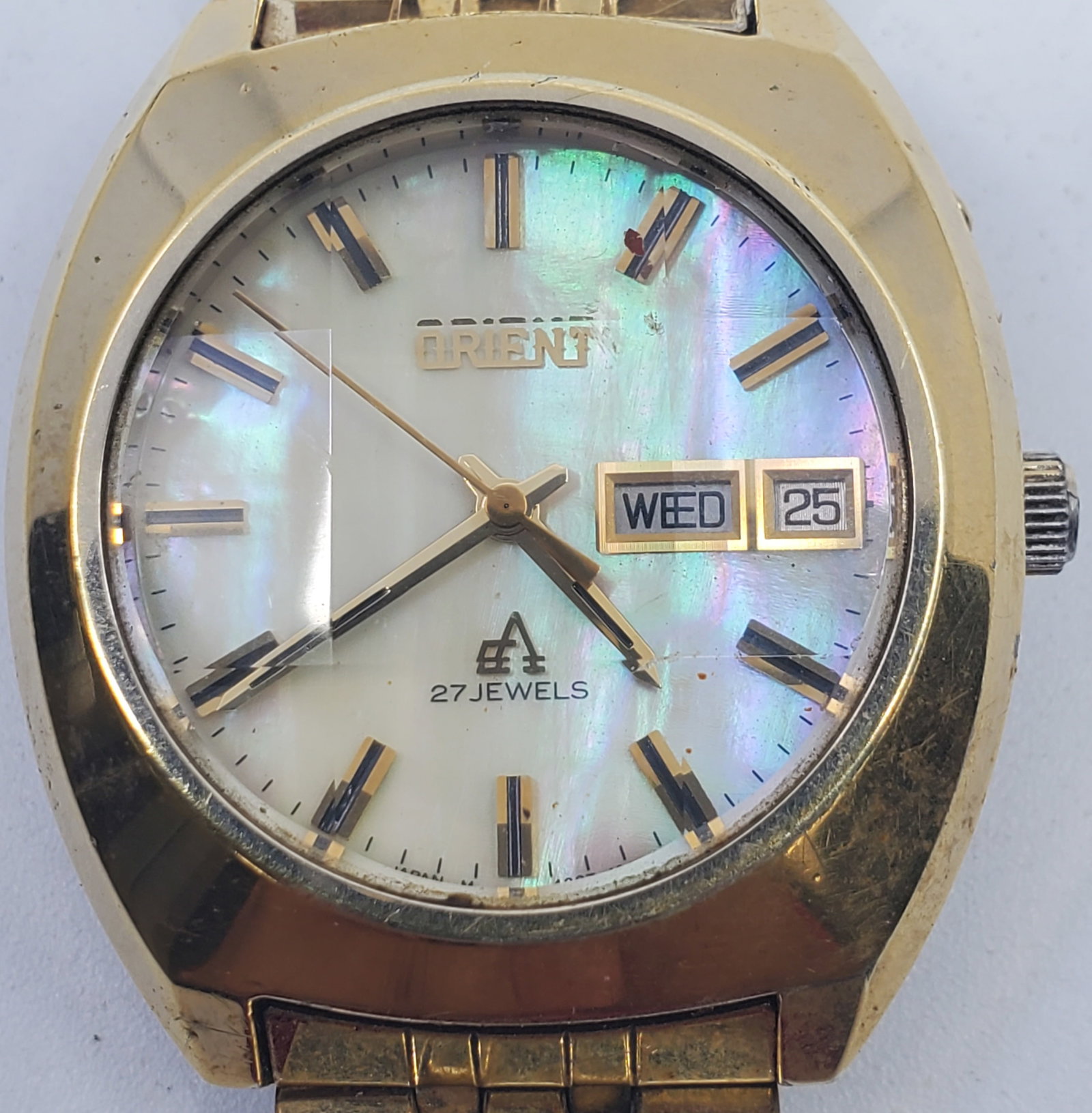Vintage Men's ORIENT Manual Wrisrwatch 27J with Date: In working order, although not verified or guaranteed for accuracy. Gold plated on siainless sreel, as is the original bracelet. Opalescent dial. Crown unlocks by pushing a small burru above which all