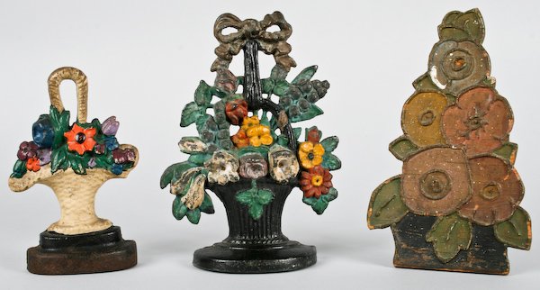 Two Vintage Cast Iron Flower Basket Doorstops: American School, 20th Century, Two Vintage Cast Iron Flower Basket Doorstops and a very Rare Wood Flower Basket Doorstop, ranging in size from 8 to 10 inches (height). Provenance: The Betty Gordon Est