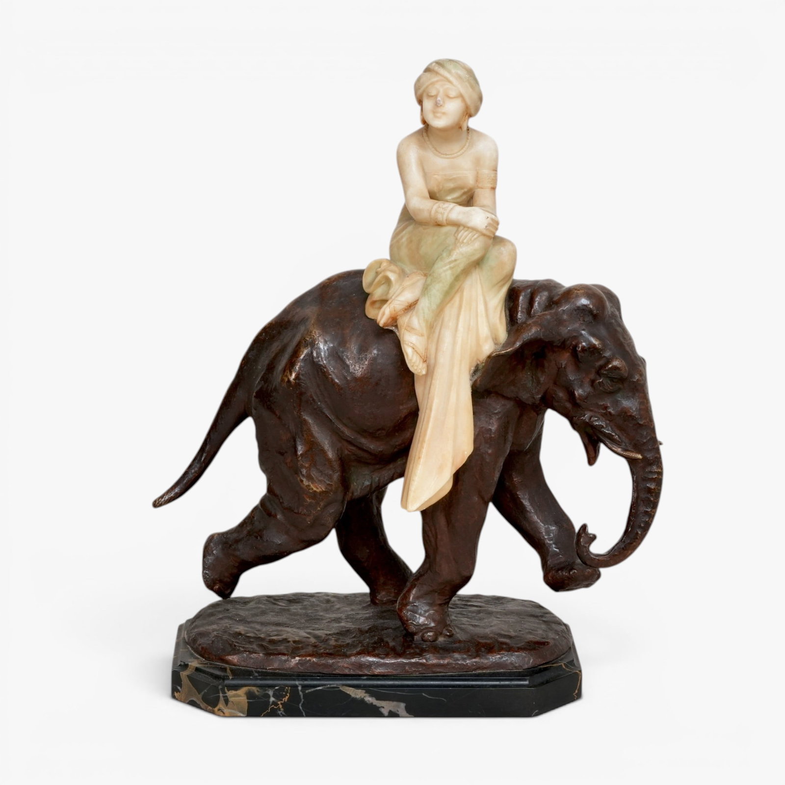 Attributed to Emilio Fiaschi (1848- 1941), Bronze and Alabaster Woman Seated on an Elephant: The woman seated to one side on the back of a striding elephant, draped in long cloths, sandals and a turban on her head, black and brown marble base etched P. G E. Fiaschi The collection of Frank and
