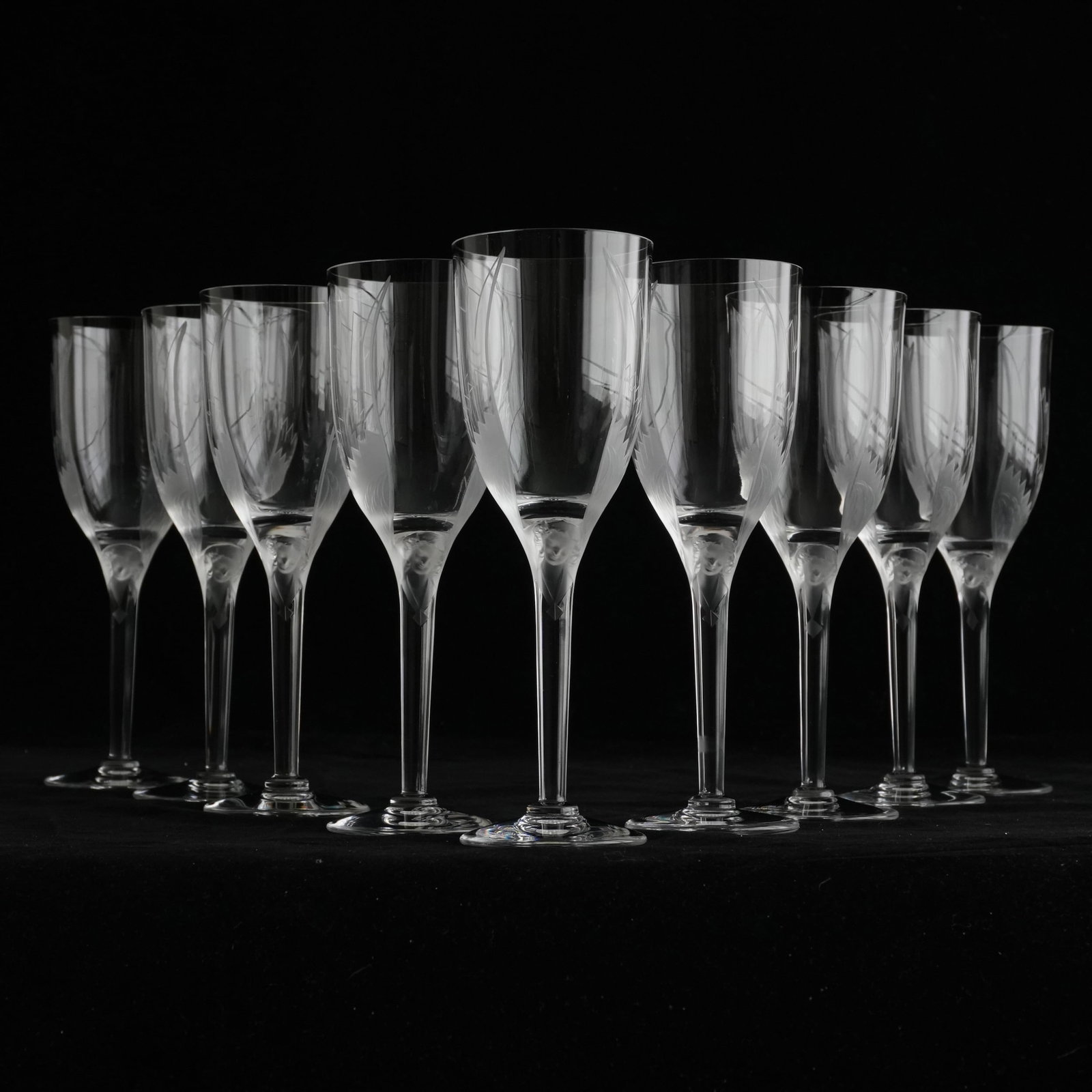 Nine French Lalique Champagne Glasses: Each with an etched wing design on clear crystal flute and molded frosted crystal angel face at top of stem, signed Lalique on underside The collection of Frank and Irene Giuffrida, owners of the