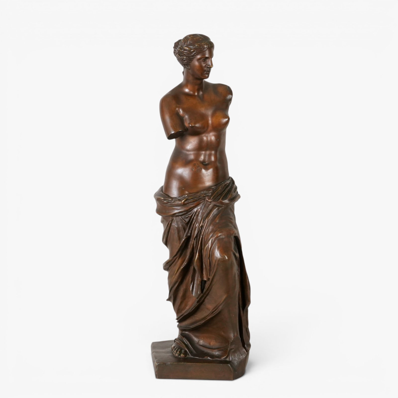 Italian School Bronze of Venus de Milo: 20th century, the classical figure standing on a squared base in contrapposto, the head looking slightly downward, the arms missing and the lower half wrapped in drapery, deep brown patina The collect