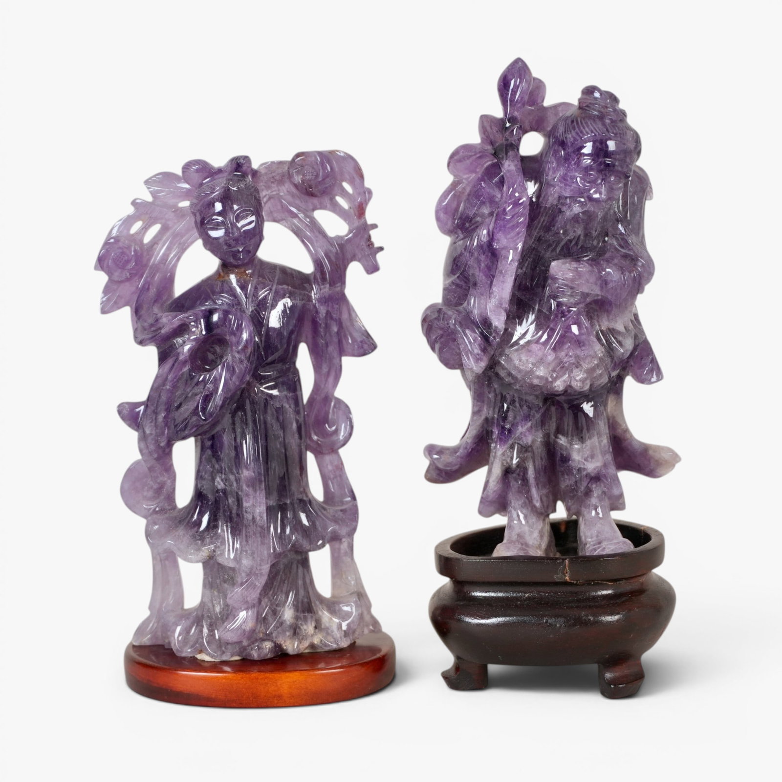 Two Chinese Amethyst Sculptures: 20th century, an immortal with a fruiting sprig over one shoulder and a standing meiren dressed in long robes and holding a blossoming branch, both stones with lighter inclusions The collection of