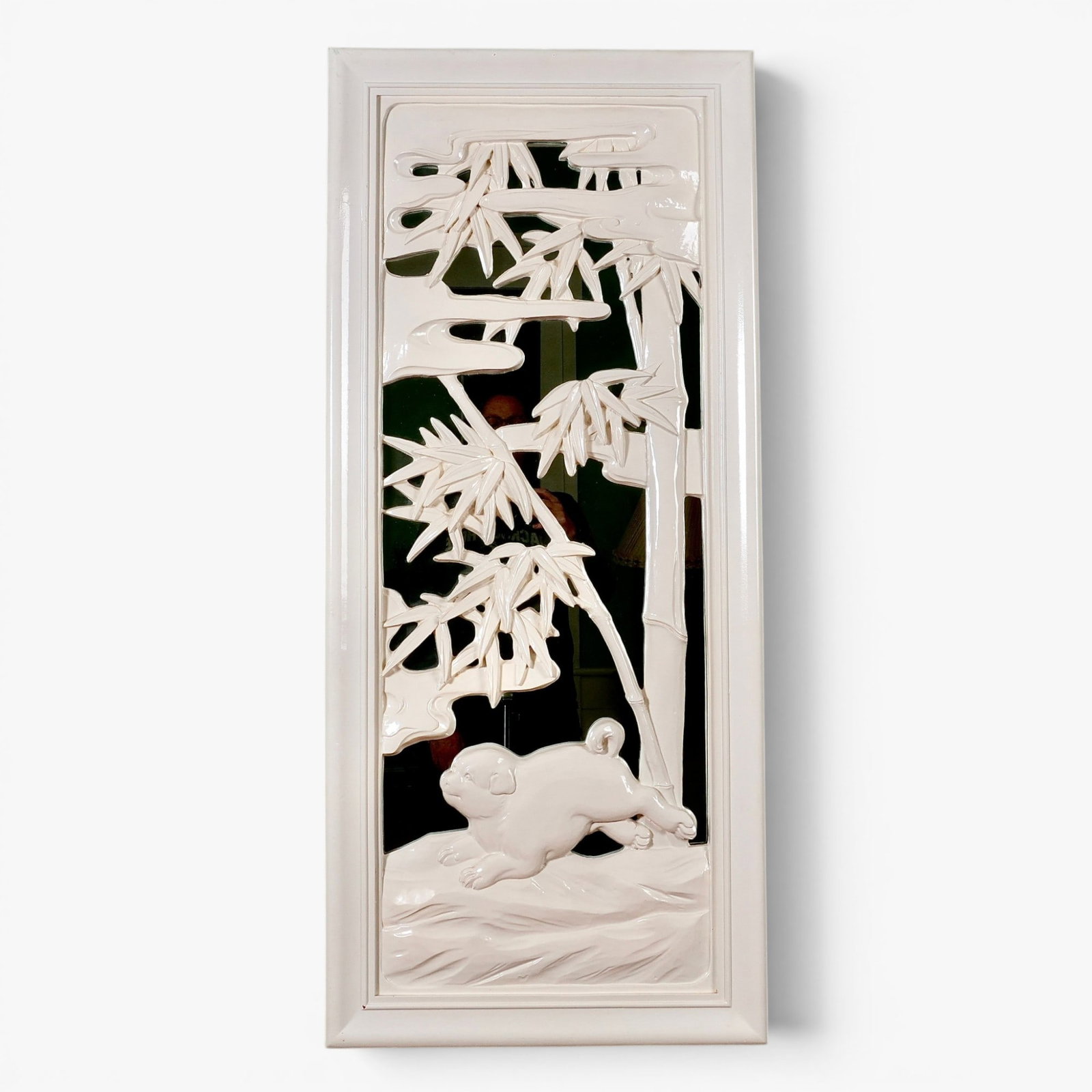 Whimsical Chinese Style Wood Mirror: 20th century, of vertical rectangular shape, the mirror overlaid with a wood scene of a puppy running below bamboo, white lacquered finish The collection of Frank and Irene Giuffrida, owners of the