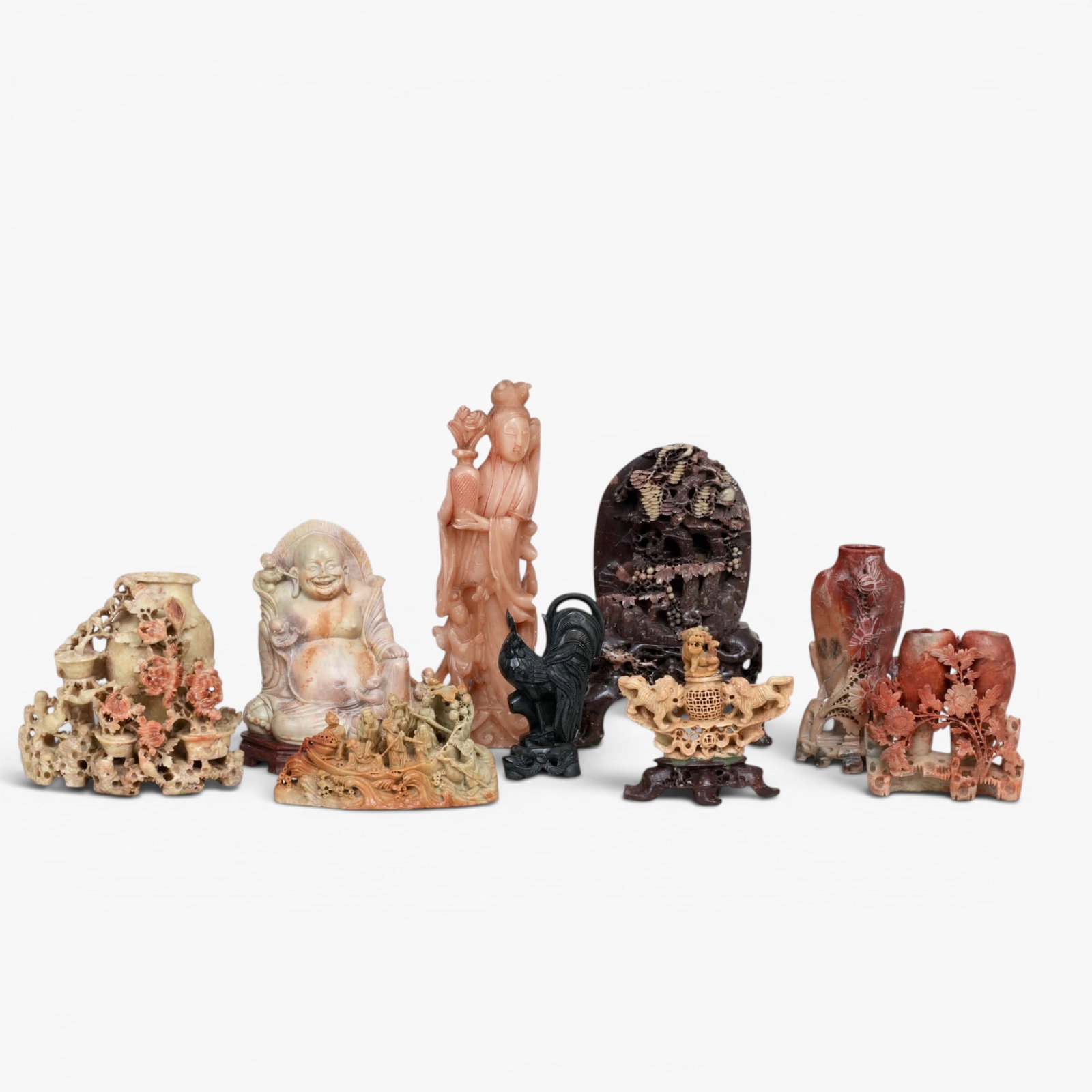 Group of Nine Chinese Soapstone Sculptures: 20th century, comprising: A single vase with blossoming chrysanthemum; squirrels frolicking amid pine and fruiting grapes with conforming base; Guanyin holding a vase, with attendant and crane; laughi