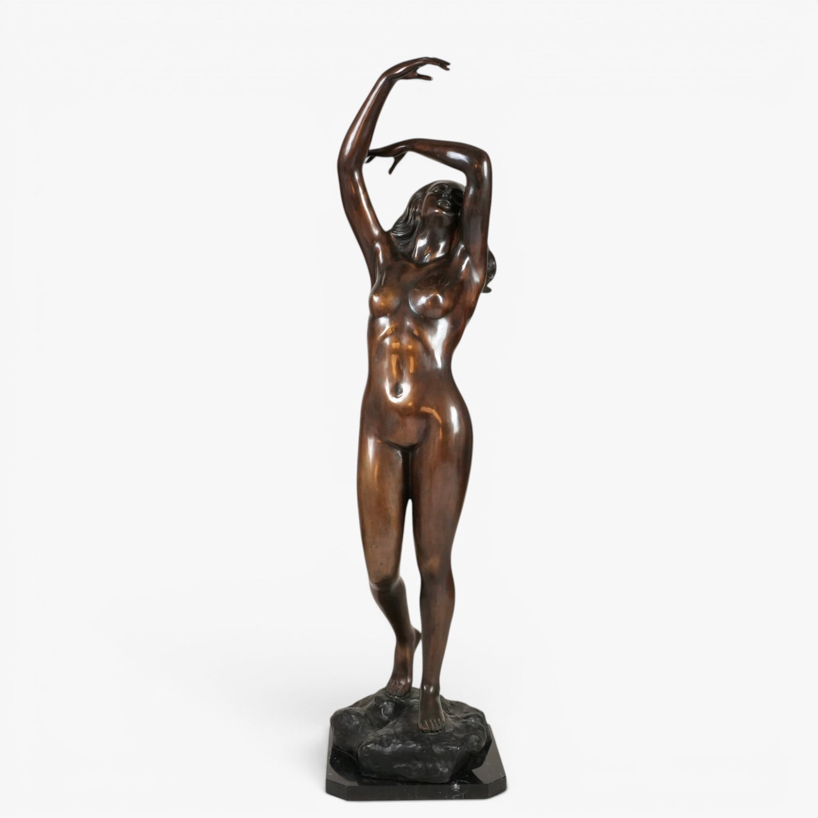 Large Italian Bronze Sculpture Depicting a Nude Woman: 20th century, signed on base S. Monaco, the figure cast in a sensual pose with her arms reaching above the head, her long hair flowing down her back, mounted on a black stone base The collection of