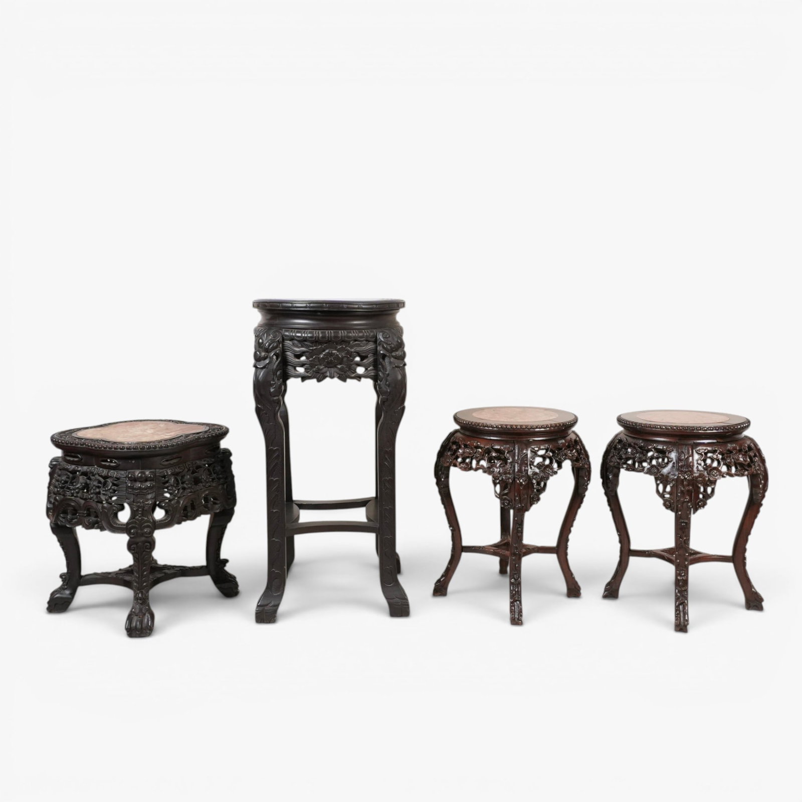 Group of Four Chinese Marble Inset Hardwood Tables: 20th century, a pair with circular marble seats set into heavily carved wood frames with a blossoming prunus motif; the other with a quatrefoil inset stone, the hardwood carved with stylized lion head