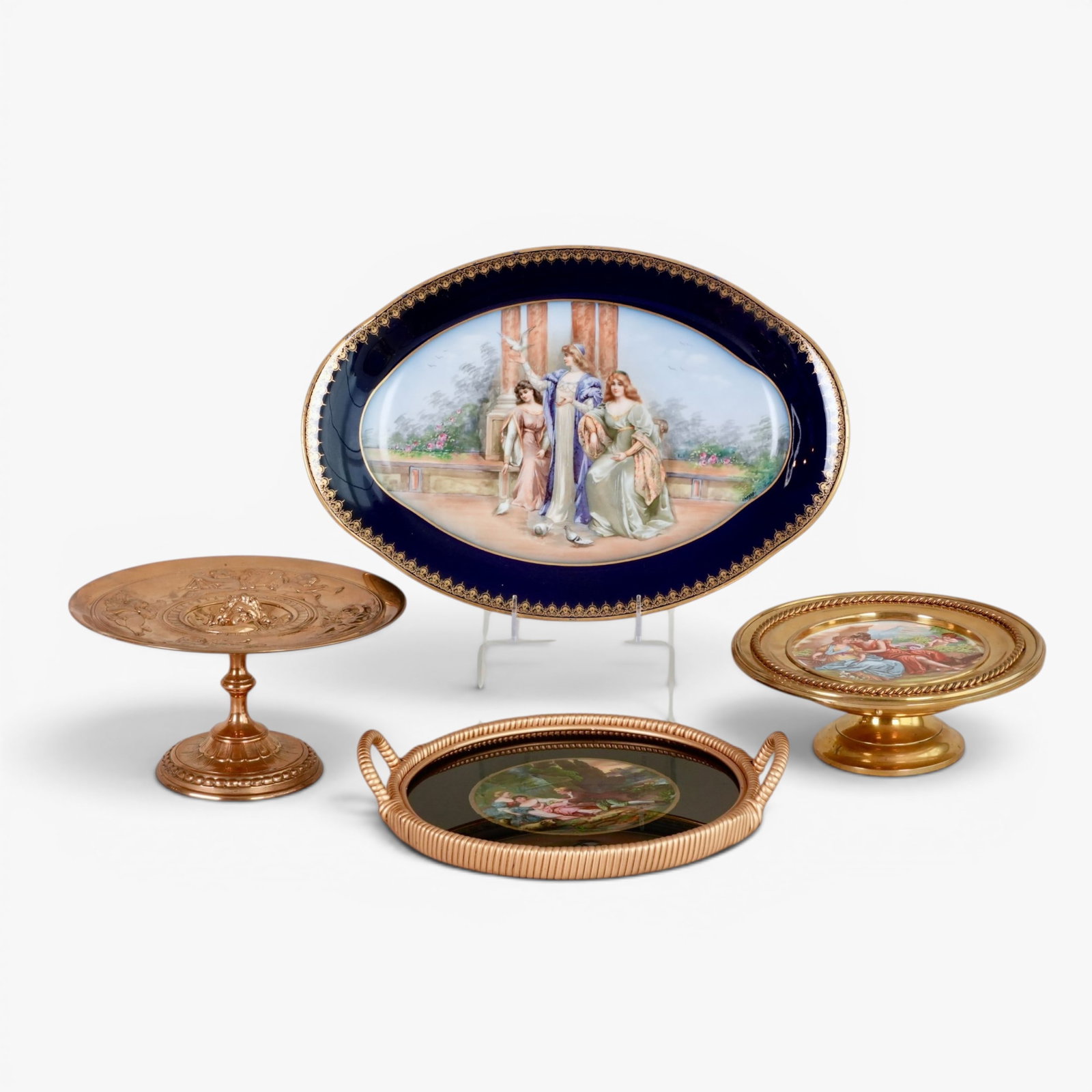 Chateau De Etoiles, Sevres Serving Platter; together with a Brass Mounted Plate and Two Tazzas: The shaped oval serving dish with red mark reading Chateau des Etoiles L S; a dish painted with romantic figures in a landscape mounted in a brass with two handles and two brass tazzas, one solid bras