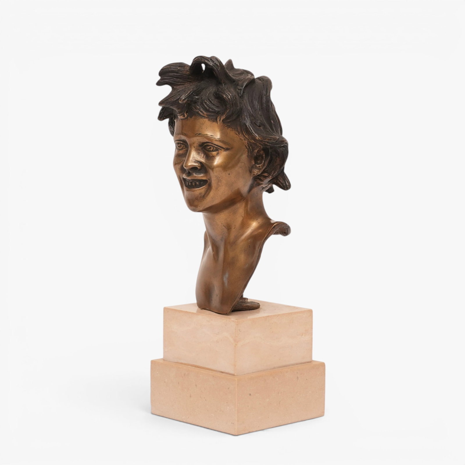 Neapolitan Style Bronze Bust of a Young Boy: The young, mischievous boy with wild hair and a grin on his face, illegibly engraved signature on reverse shoulder, mounted on a buff stone two-tier base The collection of Frank and Irene Giuffrida,