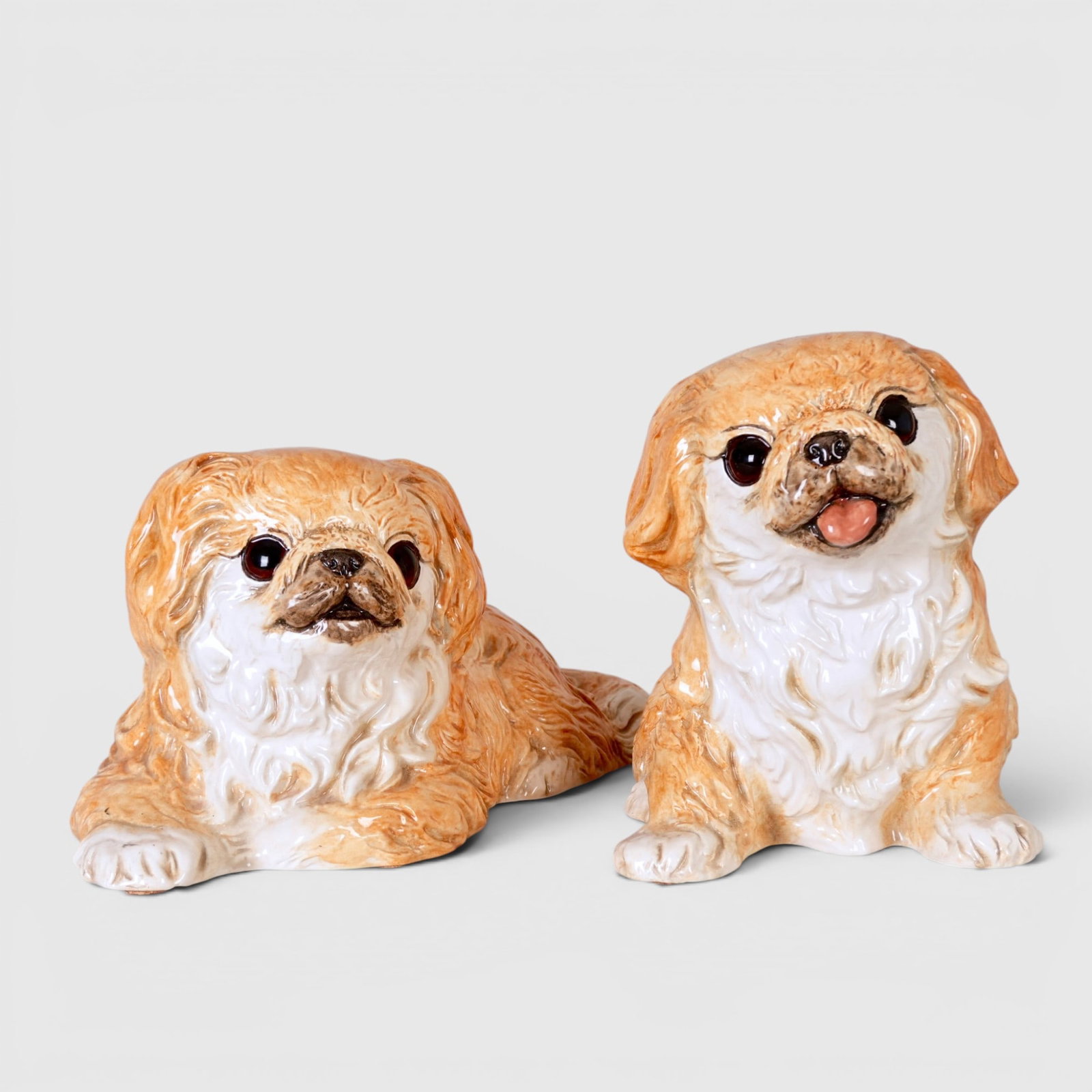 Two "The Townsends" Ceramic Pekingese Dog Sculptures, Circa 1970's-1980's: One seated, one lying down, both modeled alert and playful, numbered 154N and 155N on underside and marked "c The Townsends" The collection of Frank and Irene Giuffrida, owners of the famous Hilltop