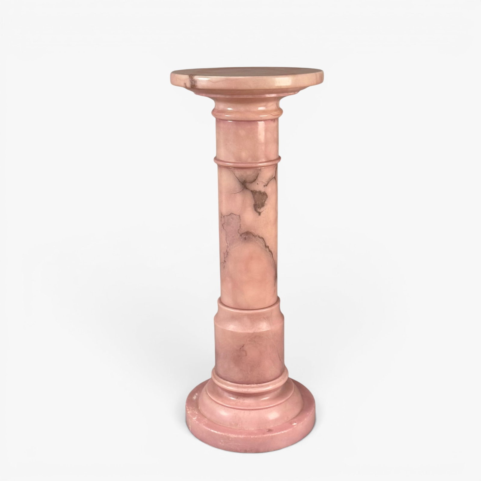 Pink Colored Marble Pedestal: 20th century, the circular top set on a cylindrical shaft carved with a wide circular base, the white stone painted in a pink tone with natural scattered dark gray veining The collection of Frank and 