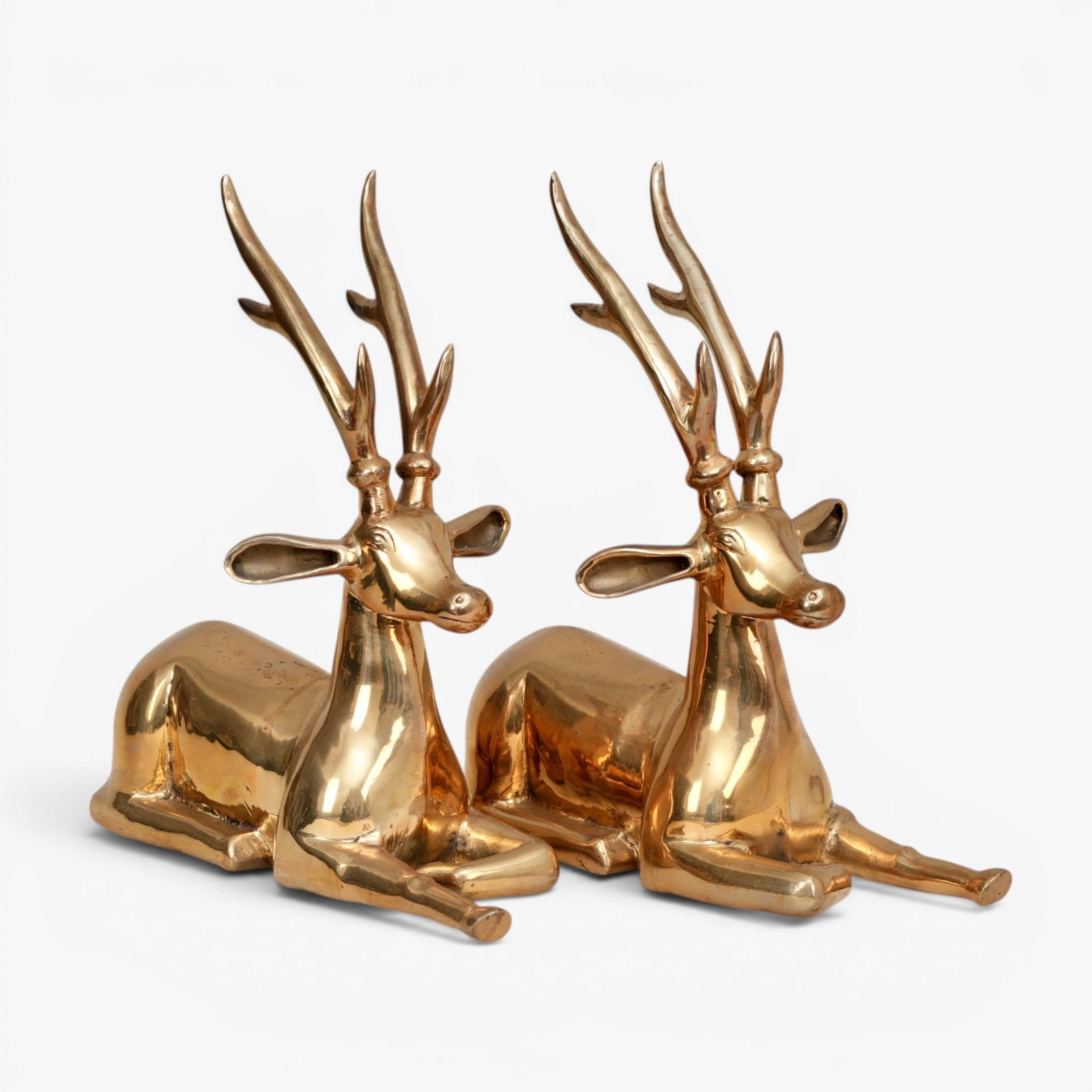 A Pair of Large Polished Brass Deer: Mid Century, sculpted in a recumbent position with heads raised beneath large antlers, one front leg outstretched The collection of Frank and Irene Giuffrida, owners of the famous Hilltop Steakhouse,