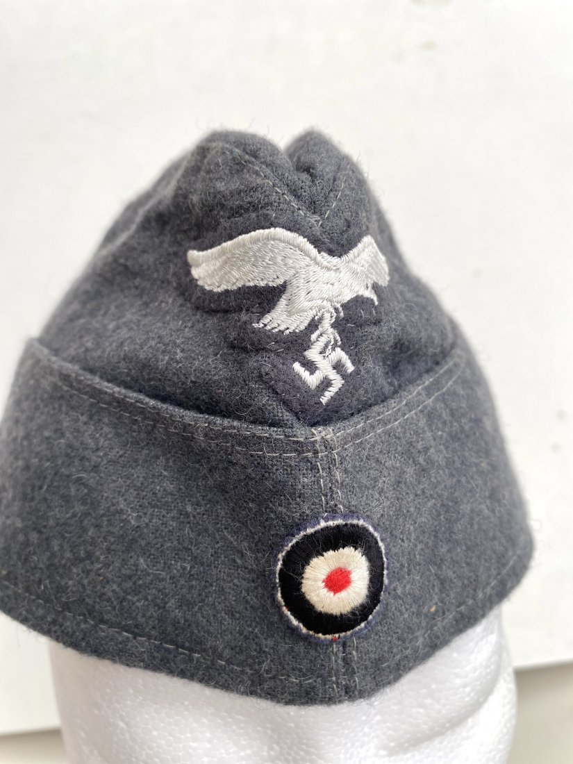 LUFTWAFFE OVERSEAS CAP GRAY NAZI WW2: A gray model Luftwaffe Overseas cap. this wool cap has a quality silver bullion Luftwaffe eagle on a wool backer sewn upon the peak of the cap at the front. inside marked with maker and size.
