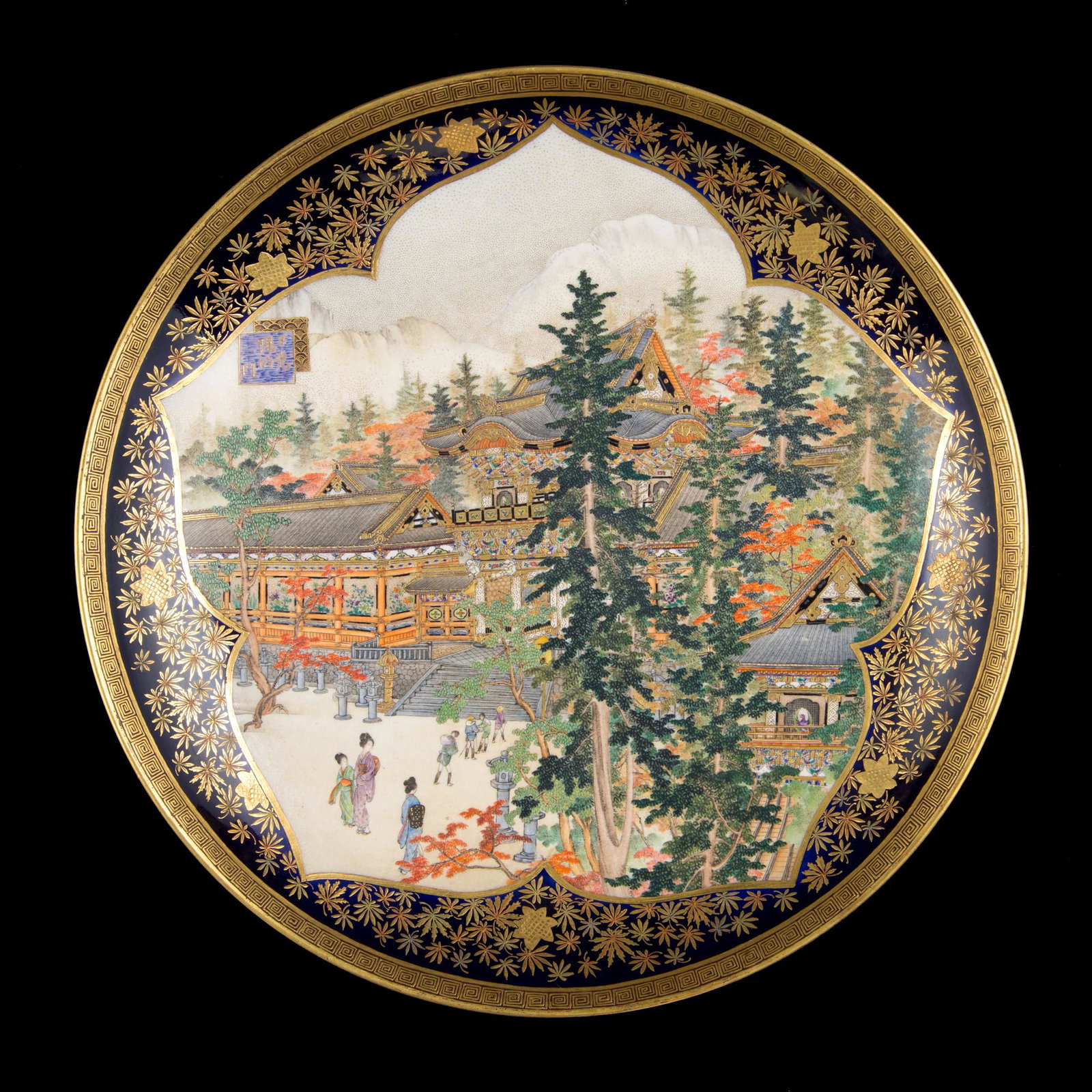 A SATSUMA DISH: d. 22 cmFinely decorated circular form within a cherry blossom-shaped reserve containing a view of the entrance to the Nikko Shrine.Signed Kyoto Kinkozan below the base.