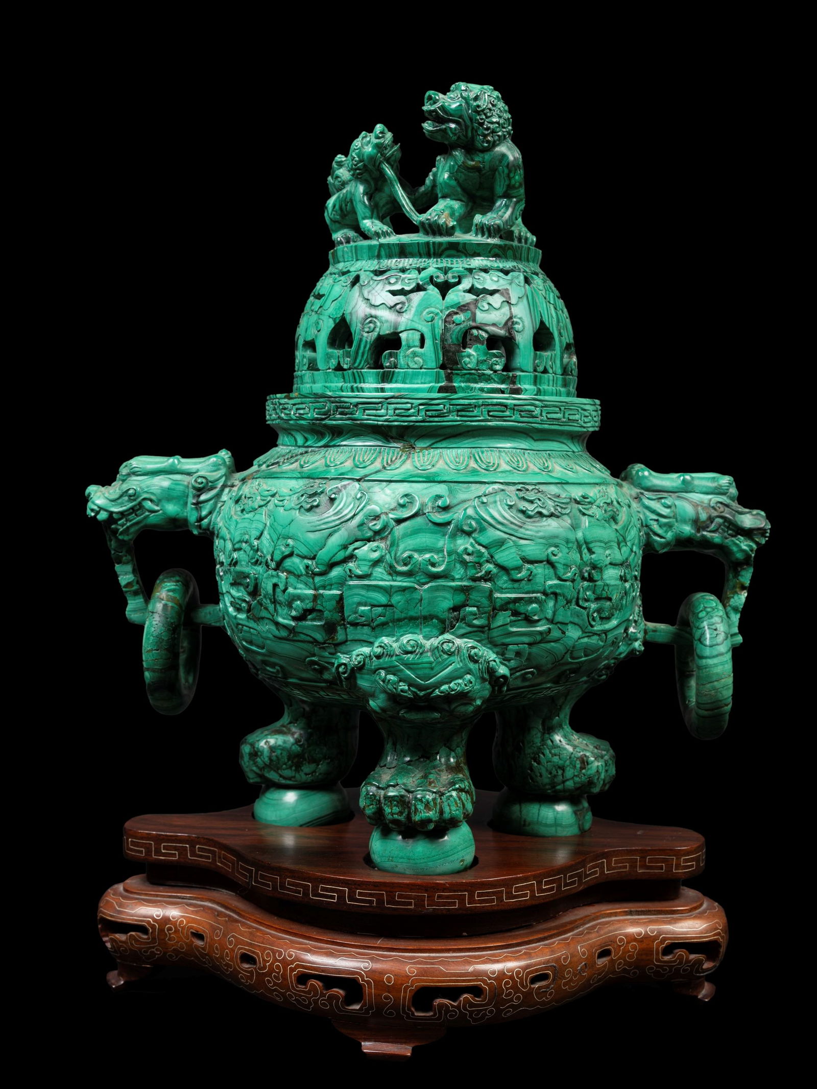 A MALACHITE TRIPOD-CENSER, China, 20th century: h cm 31 x l cm 29 Resting on three beast-form legs, the globular body is carved with *taotie* masks, while two lion-form handles at the sides hold loose rings; the pierced cover is surmounted by two l