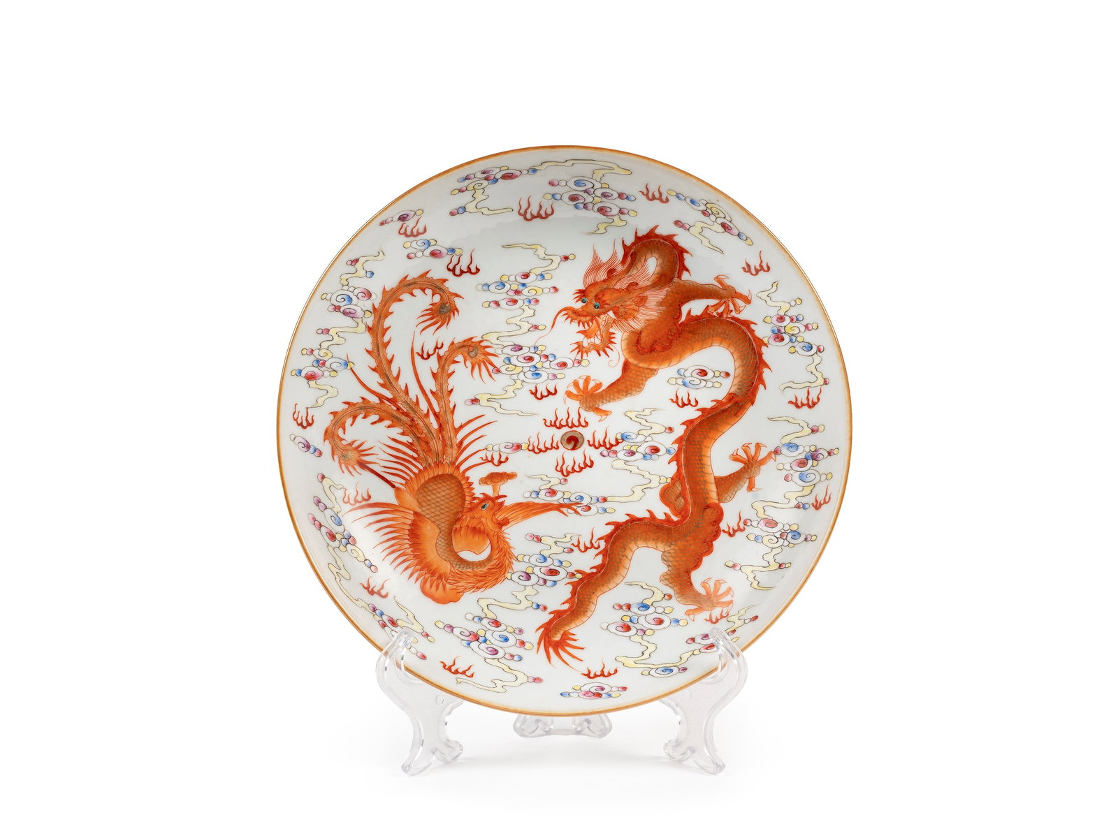 AN IRON RED FAMILLE ROSE PLATE , China, 21st century: d cm 22,2 Decorated a dragon with a phoenix playing with a pearl in iron red and gild, surrounded by clouds in Famille rose, the base decorated with wave patterns, and bears 'Da Qing Guang Xu Nian Zhi