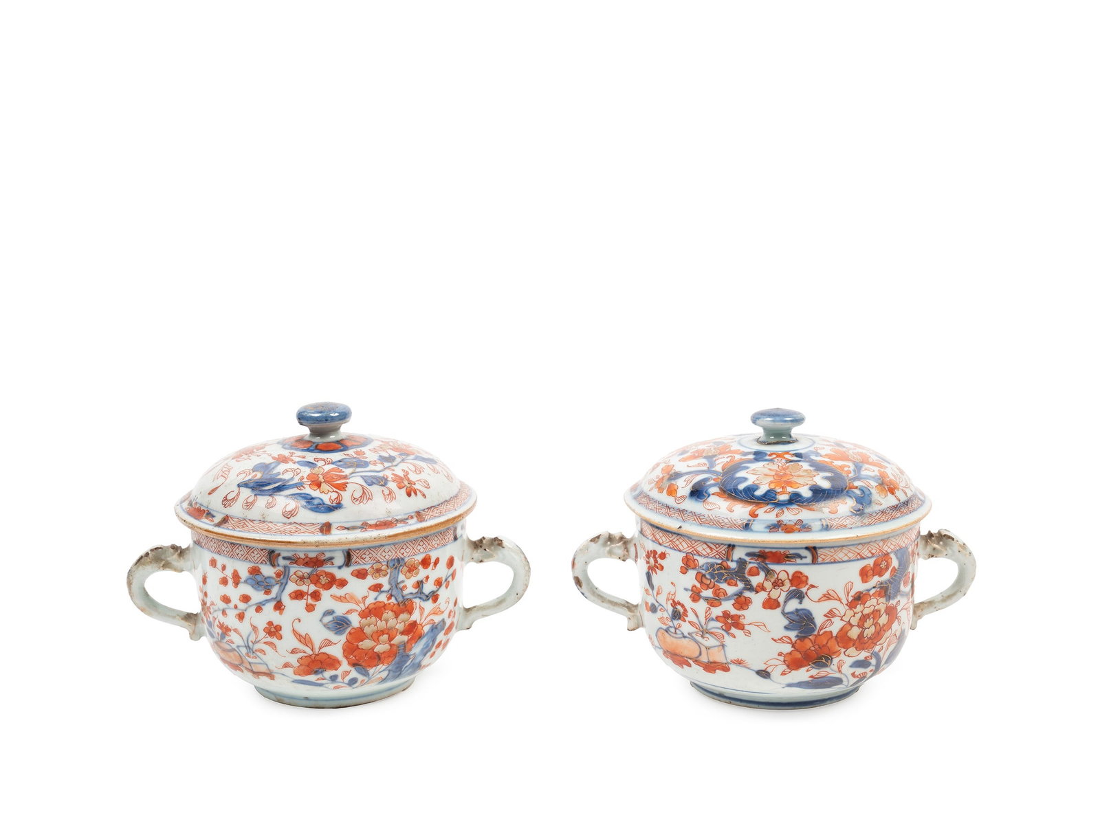 TWO PORCELAIN IMARI SUGAR BOWLS, China, Qing dynasty, Yongzheng period (1723-1735): h cm 10,5 x l cm 17,5 Decorated in underglaze blue and overglaze red and gilt, depicting to the body and cover naturalistic landscapes with flowers, trees and rocks, while the handles are shaped like