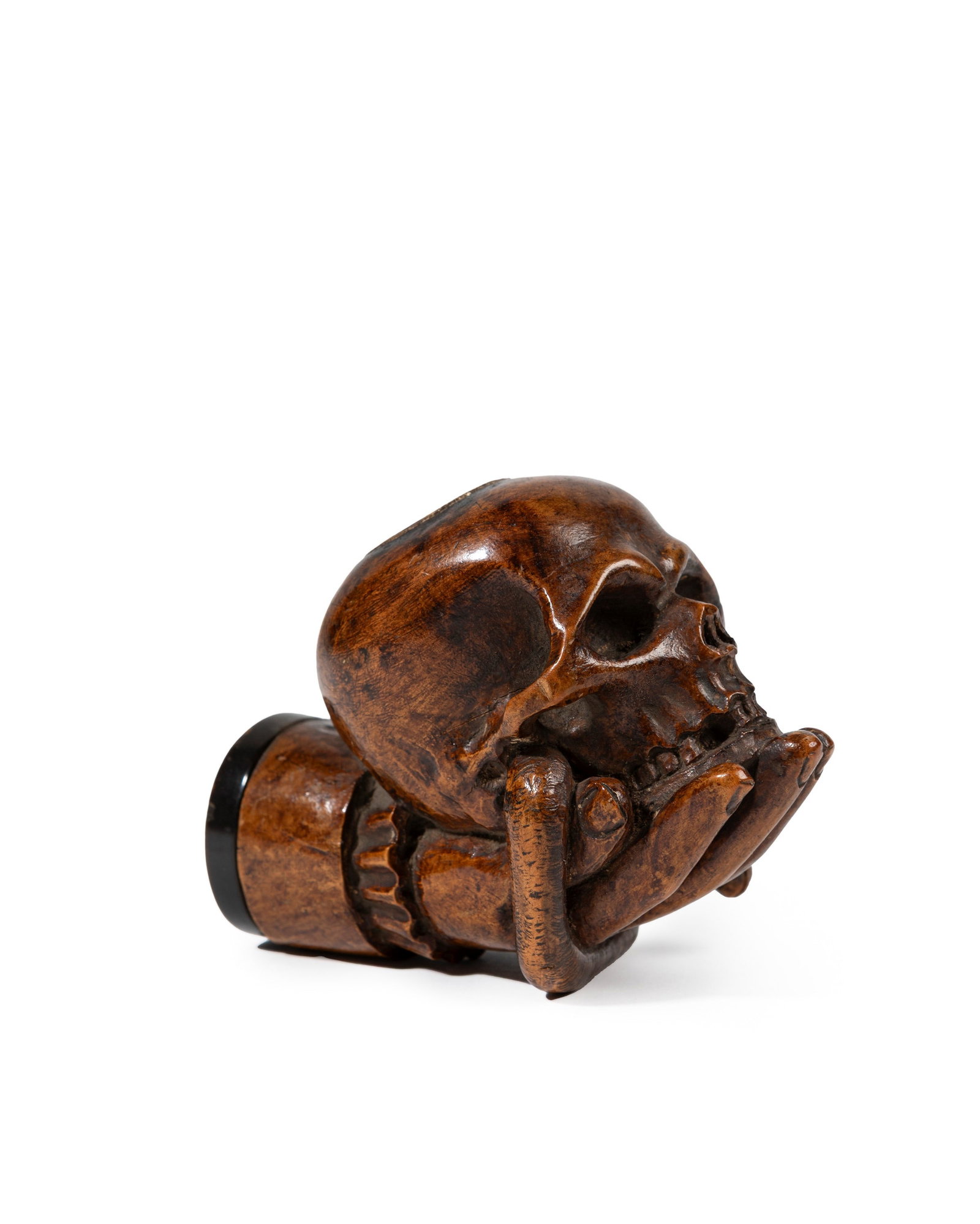 A WOODEN PIPE BOWL FINIAL, Germany, 18th century: h cm 7 x l cm 9,5.Finely carved, depicting a hand holding a skull pierced by a serpent.A similar example, from the Michael Rullier collection, was sold by Fraysse & Associés, Paris, lot 209, 11 Octob