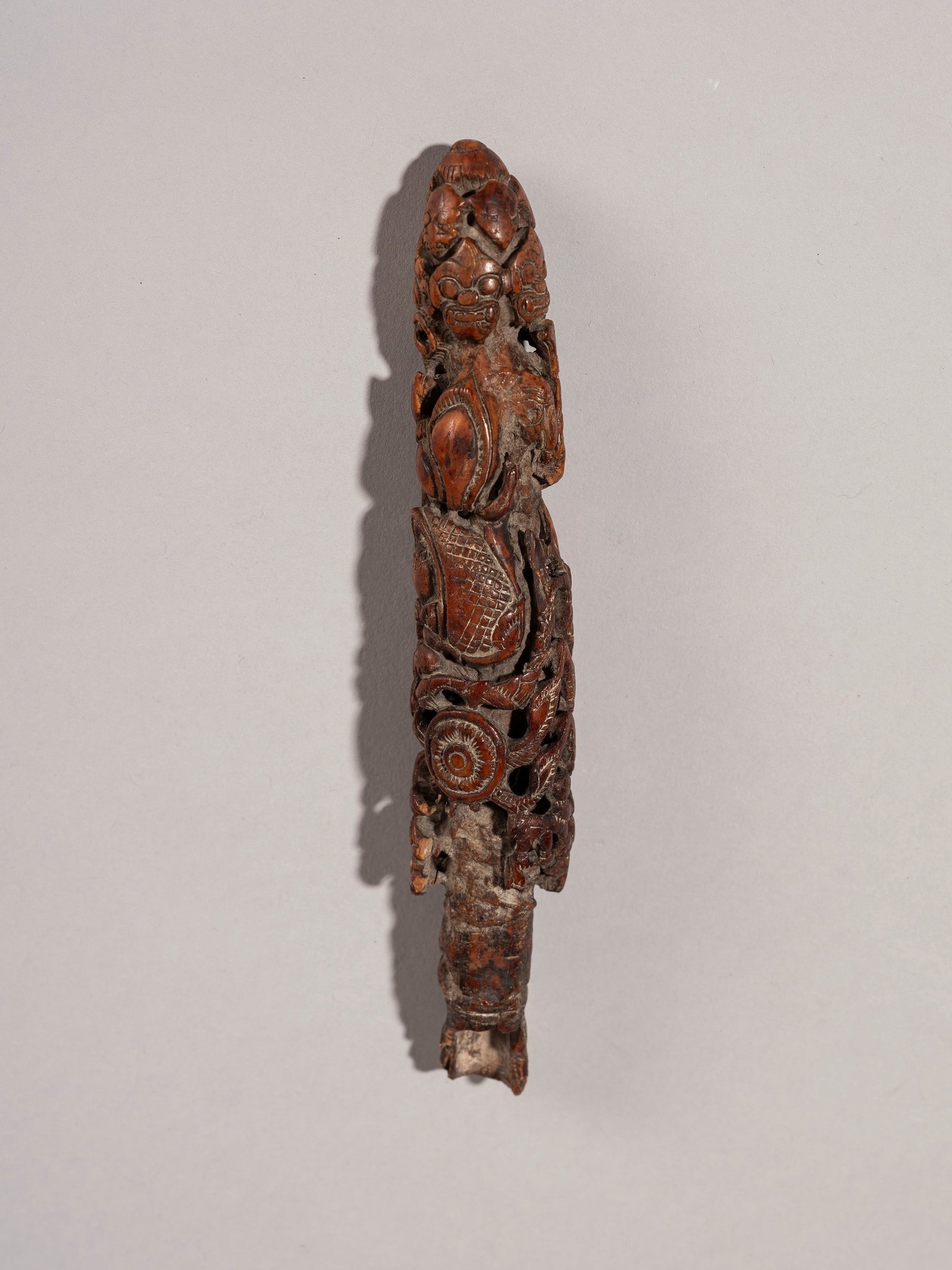 A RITUAL MORTAR PESTLE HANDLE, Bali, 19th/20th century: l cm 18 In wood, richly carved with figures from classical Balinese iconography.Provenance: Renzo Freschi Collection, Milan.