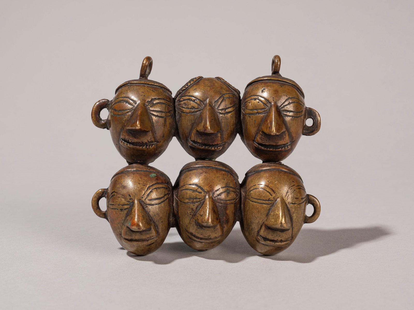 A PENDANT COMPRISING SIX BRONZE HEADS, Naga, Nagaland (1 of 3)