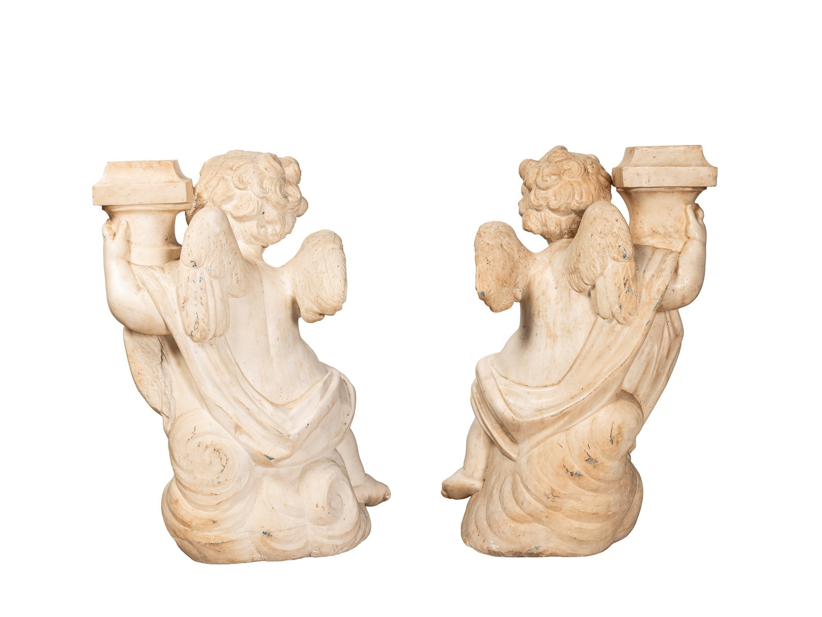 PAIR OF RARE MARBLE PUTTI CANDLEHOLDERS, Roman workshop, 17th/18th century: h cm 80 Pair of marble sculptures depicting two winged putti seated on clouds in opposing, mirrored poses. The figures, characterized by a dynamic anatomical rendering typical of the Baroque taste, su
