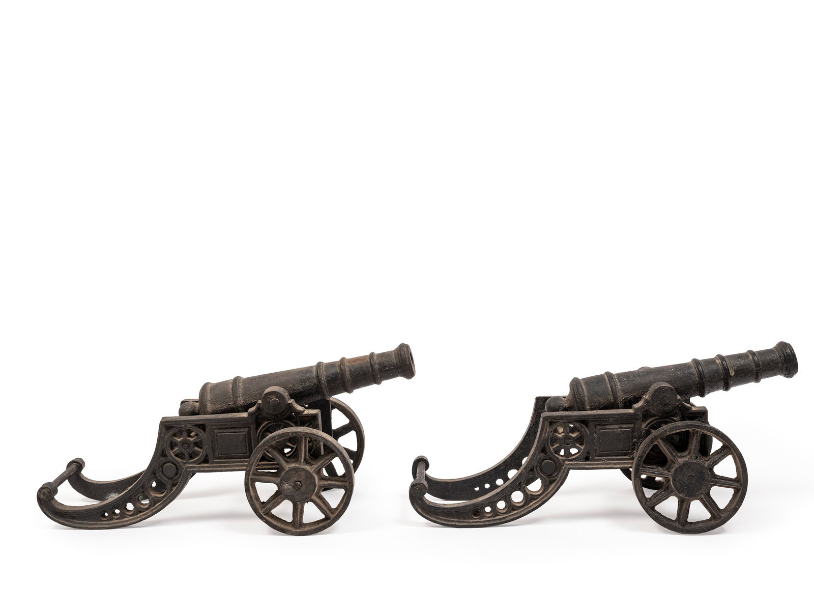 PAIR OF VICTORIAN ORNAMENTAL CANNONS, 19th century: h cm 20 x l cm 45 Turned barrel in multiple stages, mounted on a finely openwork carriage decorated with scroll motifs. Spoked wheels and a curled tail end to the carriage.