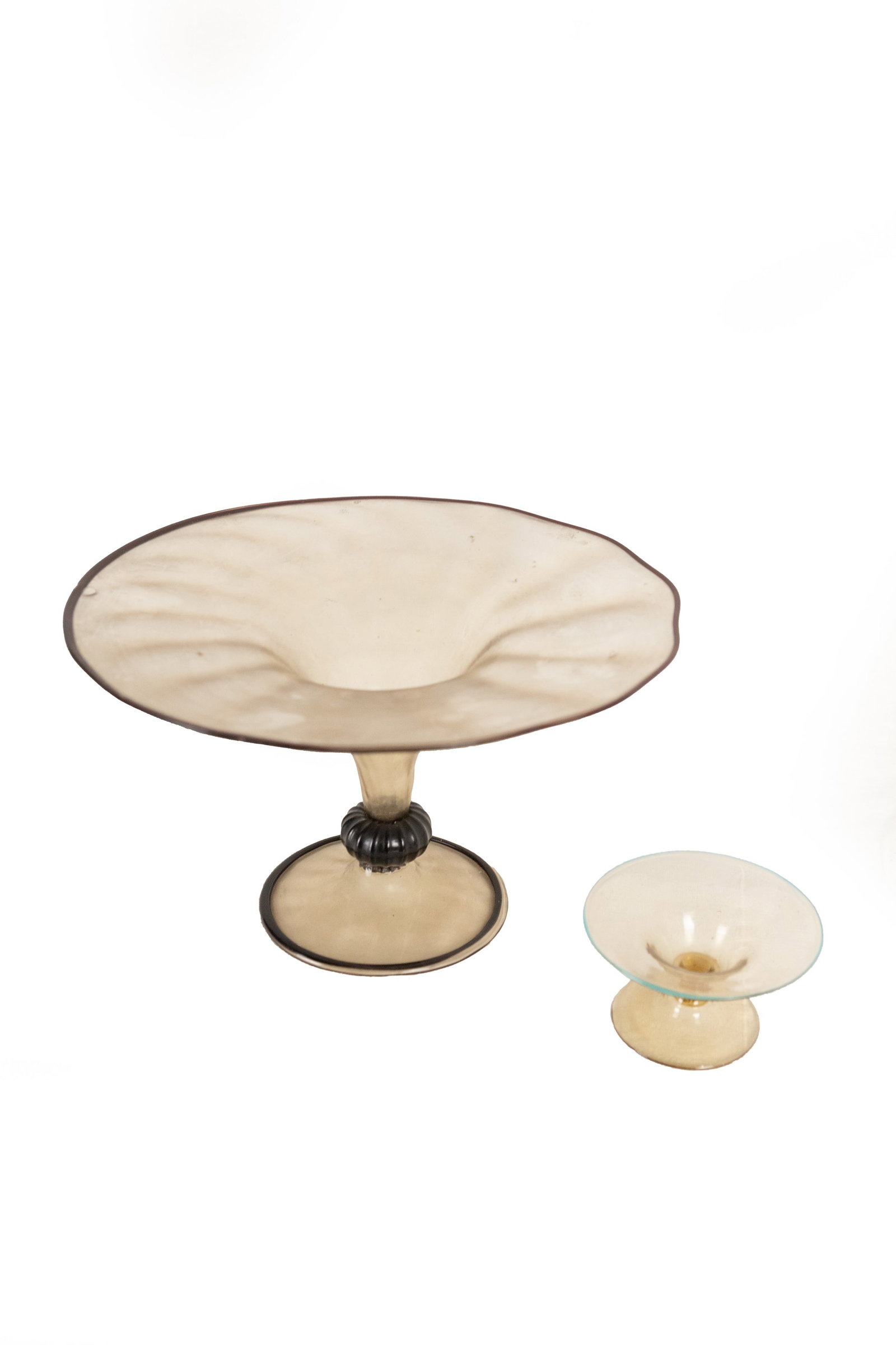 °A PAIR OF BLOWN GLASS STANDS, 20th century: h 14,5 cm × d 24,5 cm (the large one); h 5 cm × d 9 cm The large one with dark glass paste appliqués.