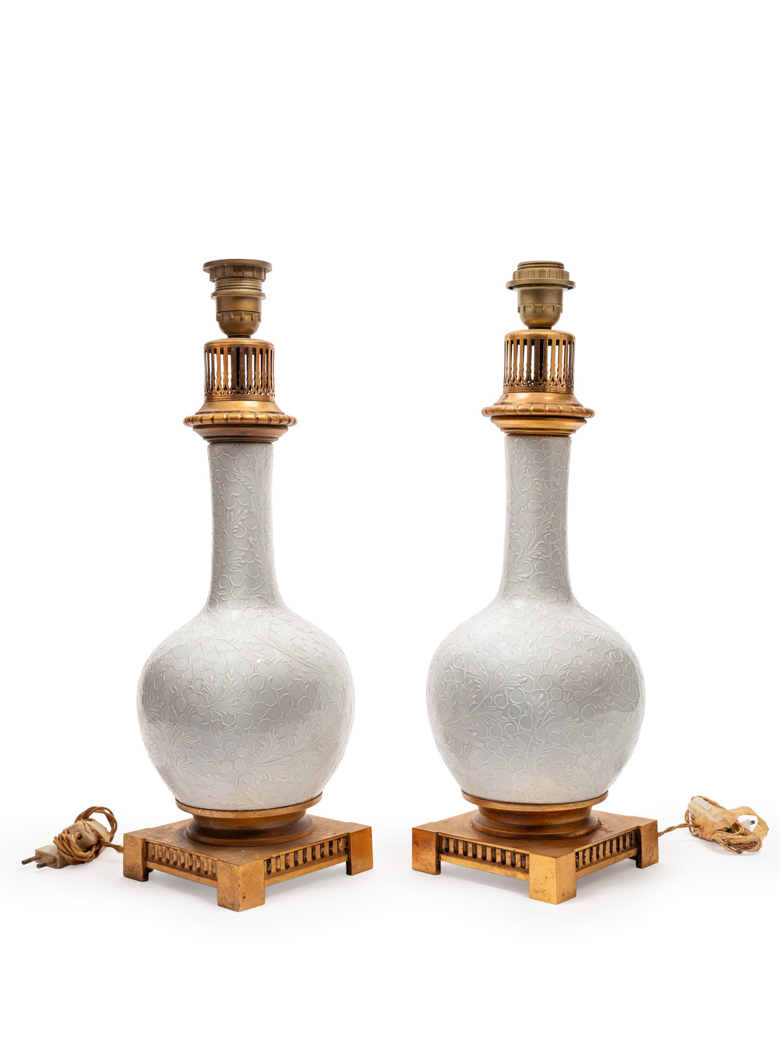 A PAIR OF WHITE PORCELAIN VASES MOUNTED AS LAMPS, France, 19th century: h tot cm 51 Bottle-shaped, they are decorated in relief with foliate scrollwork.