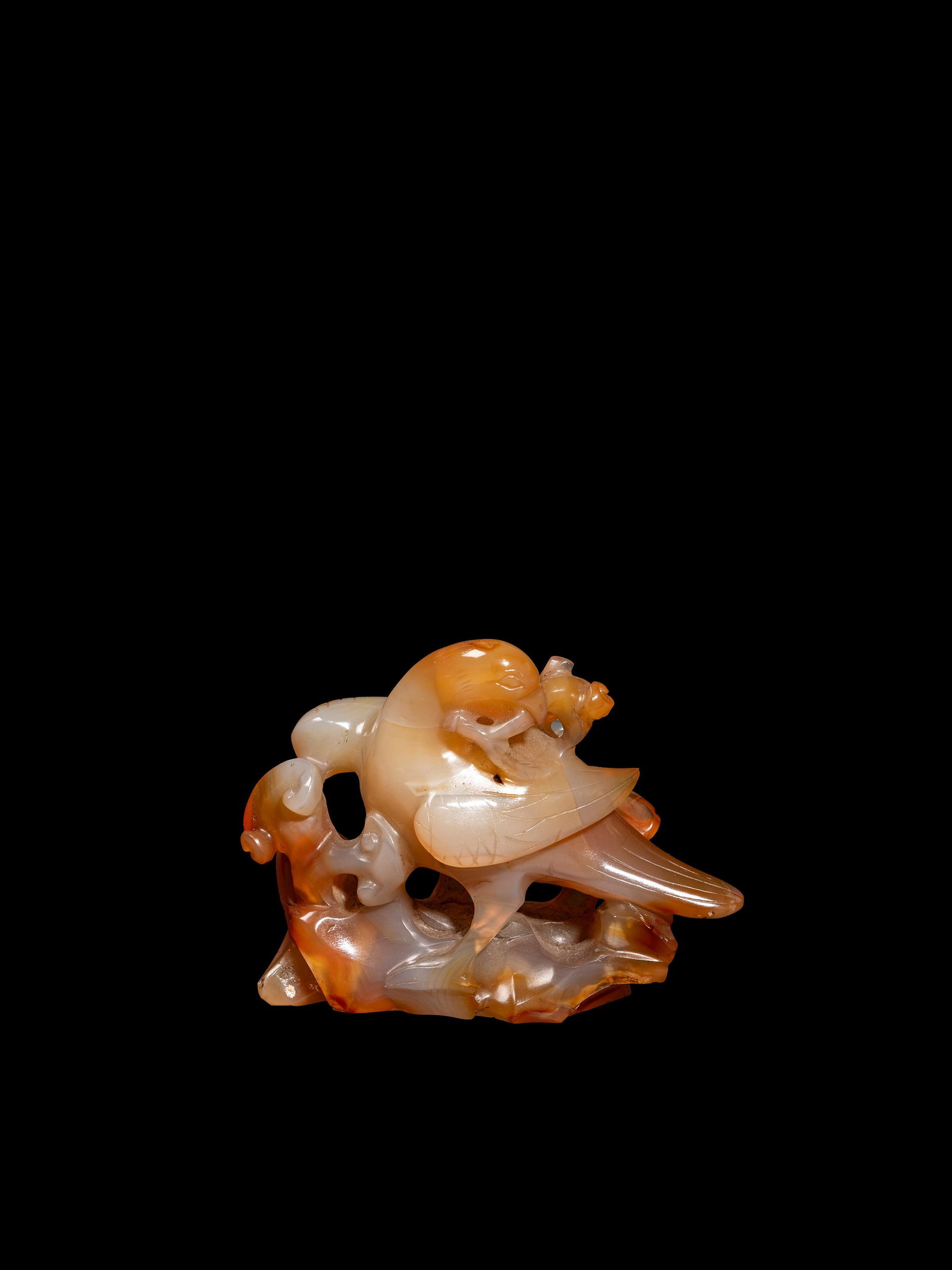 A SMALL AGATE CARVING, China, Qing dynasty (1644-1911): h cm 7 x l cm 9 Depicting a bird on a rock with lingzhi, holding a ruyi in its beak.清 (1644-1911) 玛瑙俏色雕喜上眉梢摆件