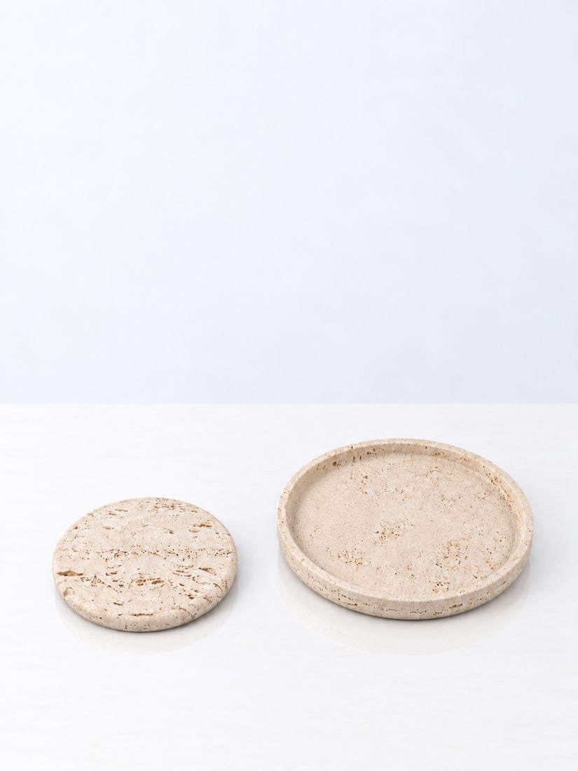 Sergio Asti (Milano 1926 - 2021), CENTREPIECES, circa 1970s: h cm 3,5 x d cm 30; h cm 2,5 x d cm 20 Set of two. Travertine. Produced by Up & Up, Massa Carrara, Italy. Manufacturer's label present.