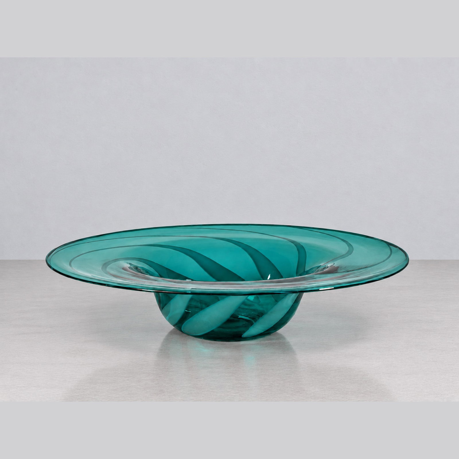 Owe Thorssen e Brigitta Karlsson, VENINI CENTREPIECE BOWL, circa 1980s: d cm 34 Green-tinted blown glass from the "Piume" series with lattimo cane decoration. Diamond-point engraved Venini Italia signature. Produced by Venini, Murano, Italy.