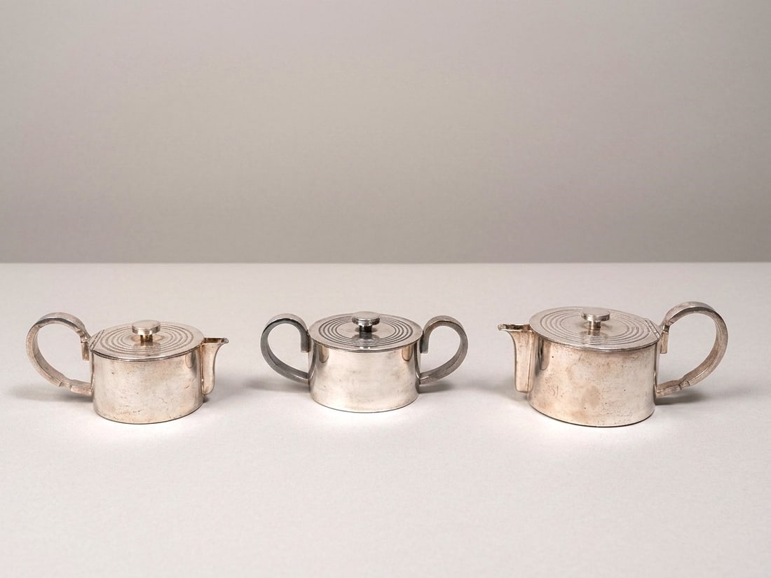 Gio Ponti (Milano 1891 - 1979), "V TRIENNALE" TEA SERVICE, 1933: h cm 10 x d cm 11 x l cm 20 Set of three pieces. Silver-plated alpacca, manufacturer's mark on the bottom. Arthur Krupp production, Milan, Italy.Catalogue Notes:Published in Domus 133 (January 1939), 