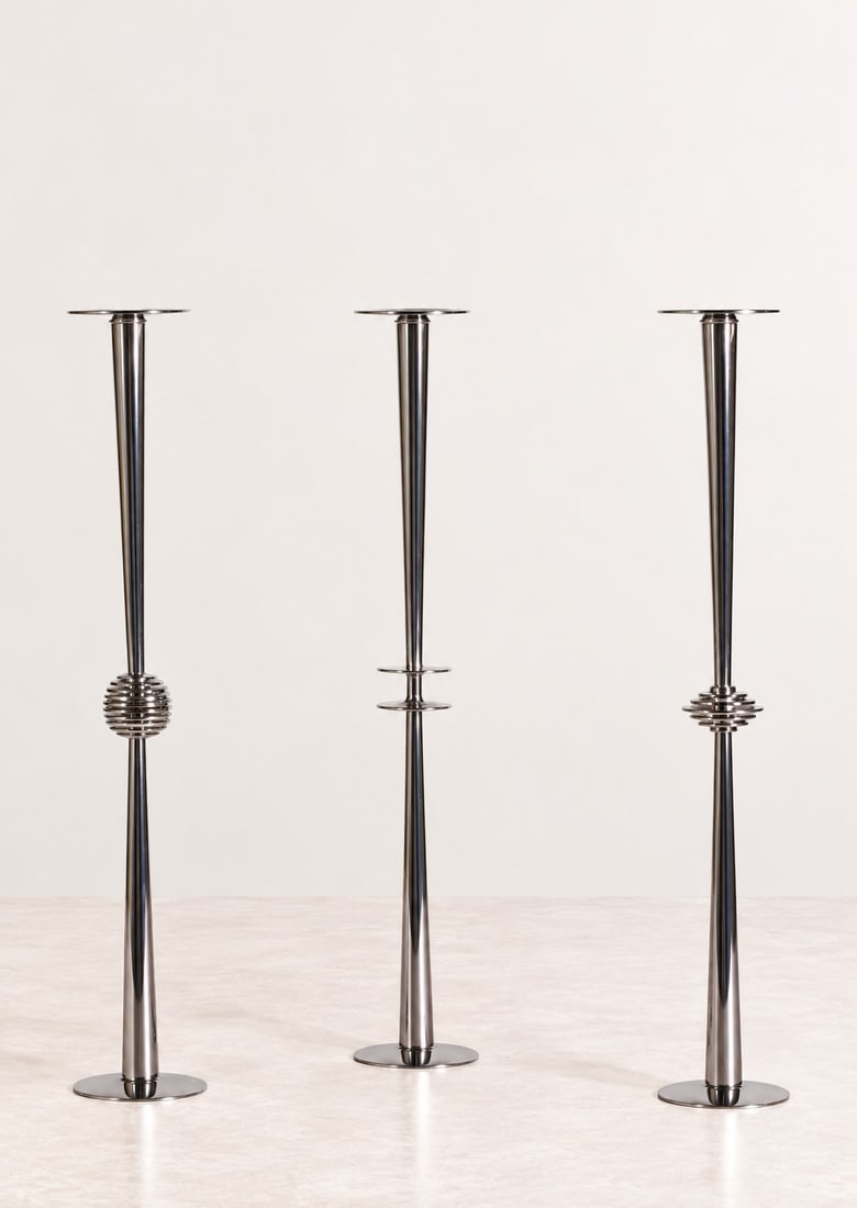 Lino Sabattini (Bregnano 1925 - 2016), CANDLESTICKS, circa 1970s: h cm 43 x d cm 6,5 Set of three. Silver-plated metal. Mark to the underside. Produced by Lino Sabattini, Italy.