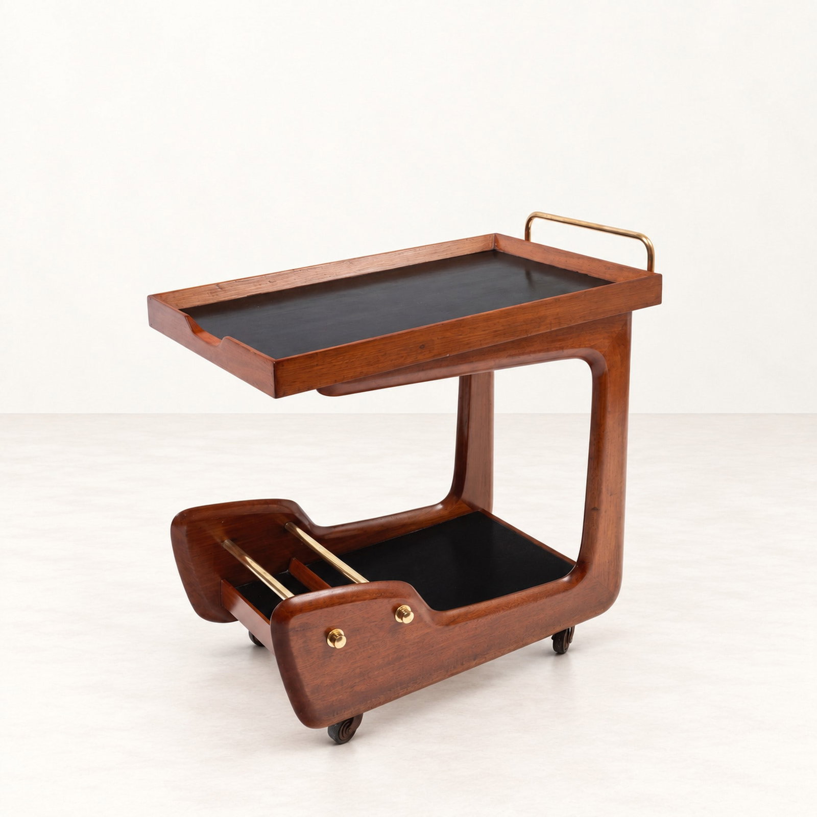 SERVING TROLLEY, circa 1960s: l cm 70 x h cm 64 x w cm 40 Wood with black laminated shelves, brass details and castors. South American production.
