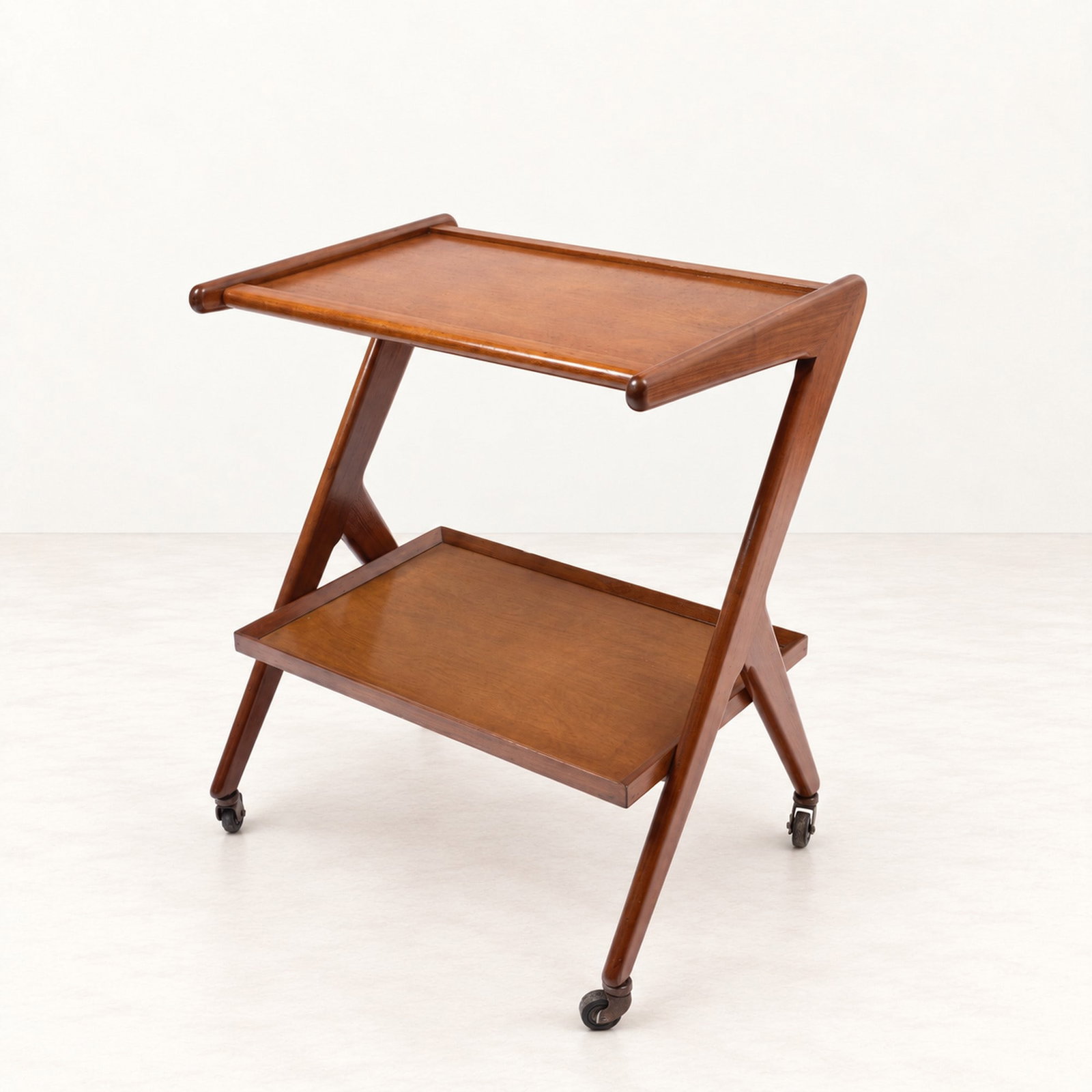 SERVING TROLLEY, circa 1950s: l cm 63 x h cm 74 x p cm 47 Wood with two shaped shelves and metal castors. South American production.