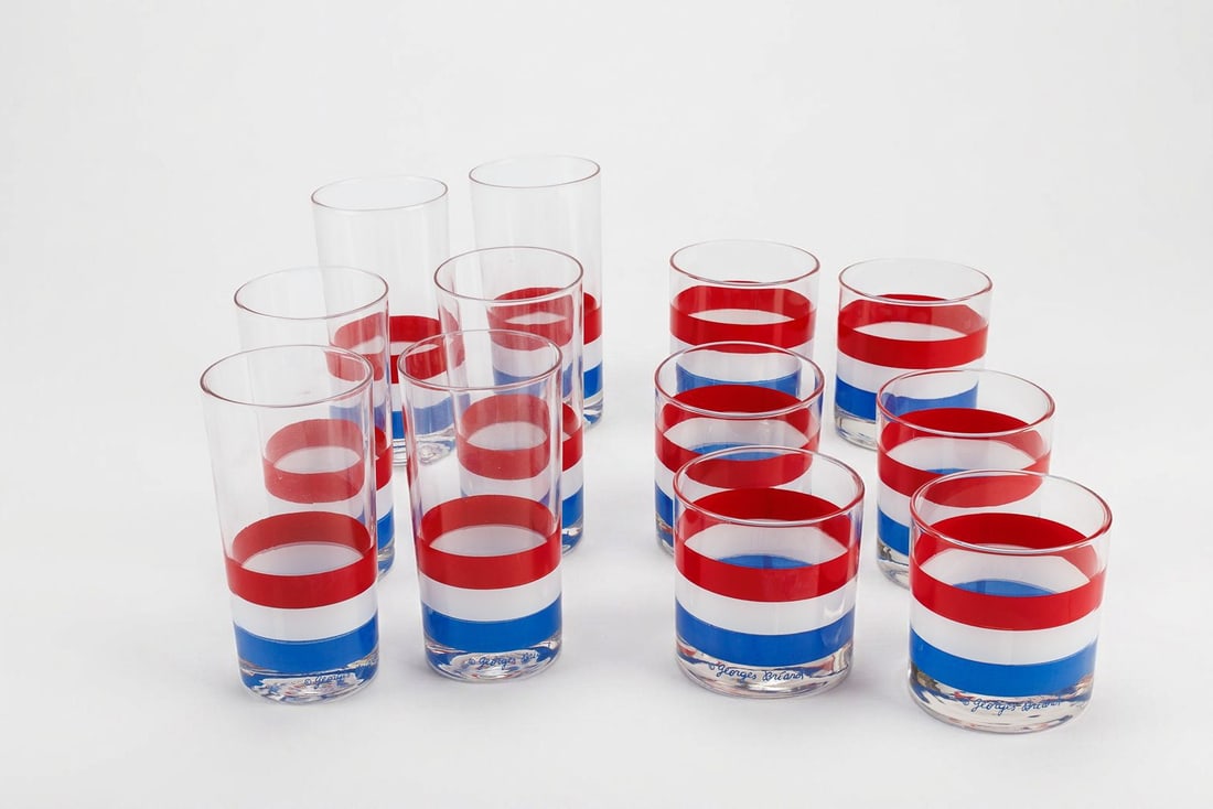 Two Sets of Vintage Georges Briard MCM Glasses in Red, White, and Blue: By Georges Briard, these two matched sets of six mid-century modern glasses is decorated throughout with eye-catching stripes of red, white, and blue. Each glass exhibits the maker's signature along