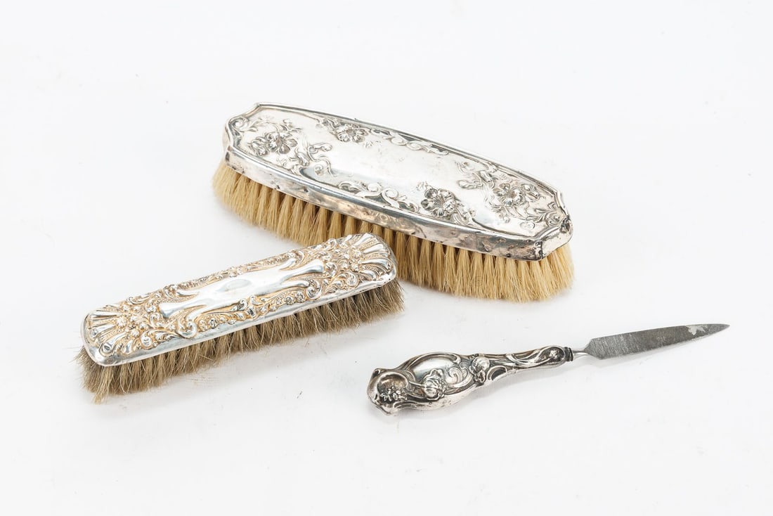 Sterling Silver Brushes and File: Two repoussé sterling silver clothes brushes and one nail file, all marked Sterling.