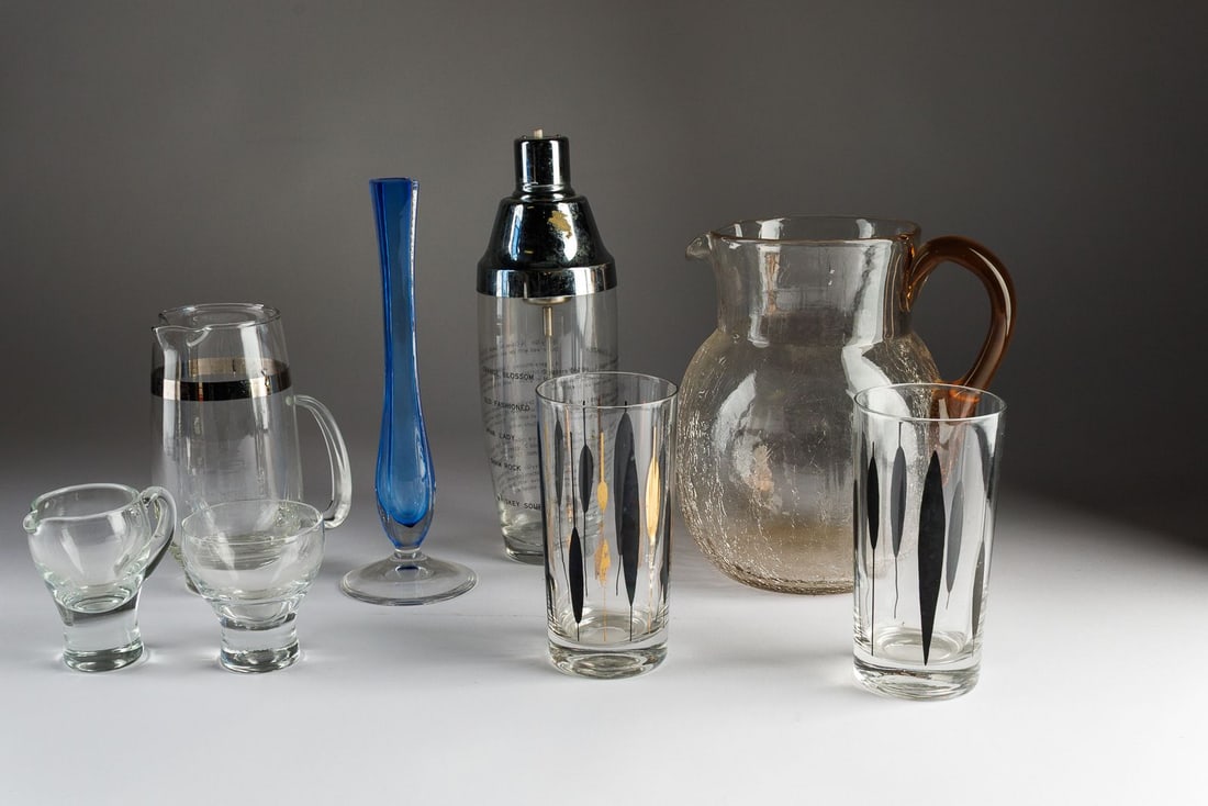 Group of Glass Serving Items: Includes a crackle glass pitcher, two highball glasses, a vintage battery operated drink stirrer, a banded pitcher, and two small glasses.