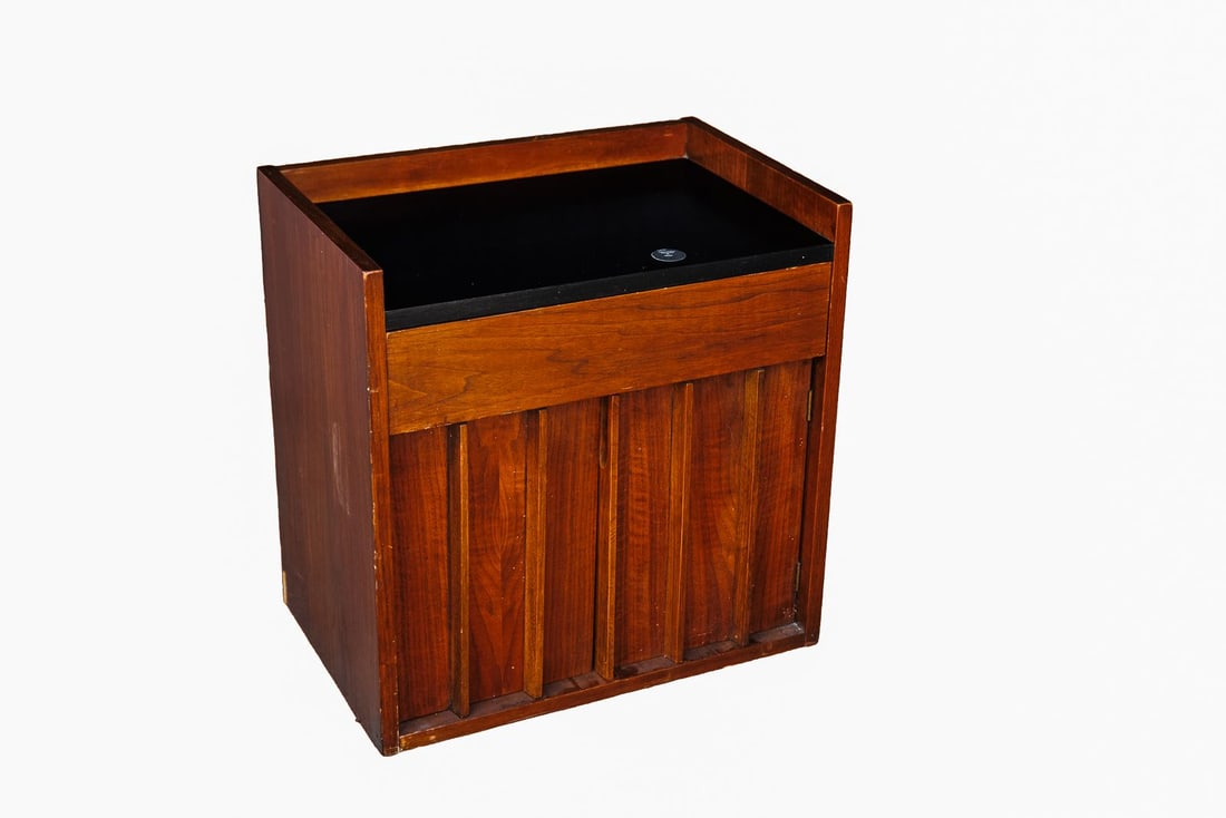 Vintage MCM Kent Coffey Teak Bar Cabinet: Dated vintage, this bar cabinet by Kent Coffey is crafted from sleek teak wood and serves as a versatile find for the mid-century modern home. This cabinet is crowned with a black laminate top